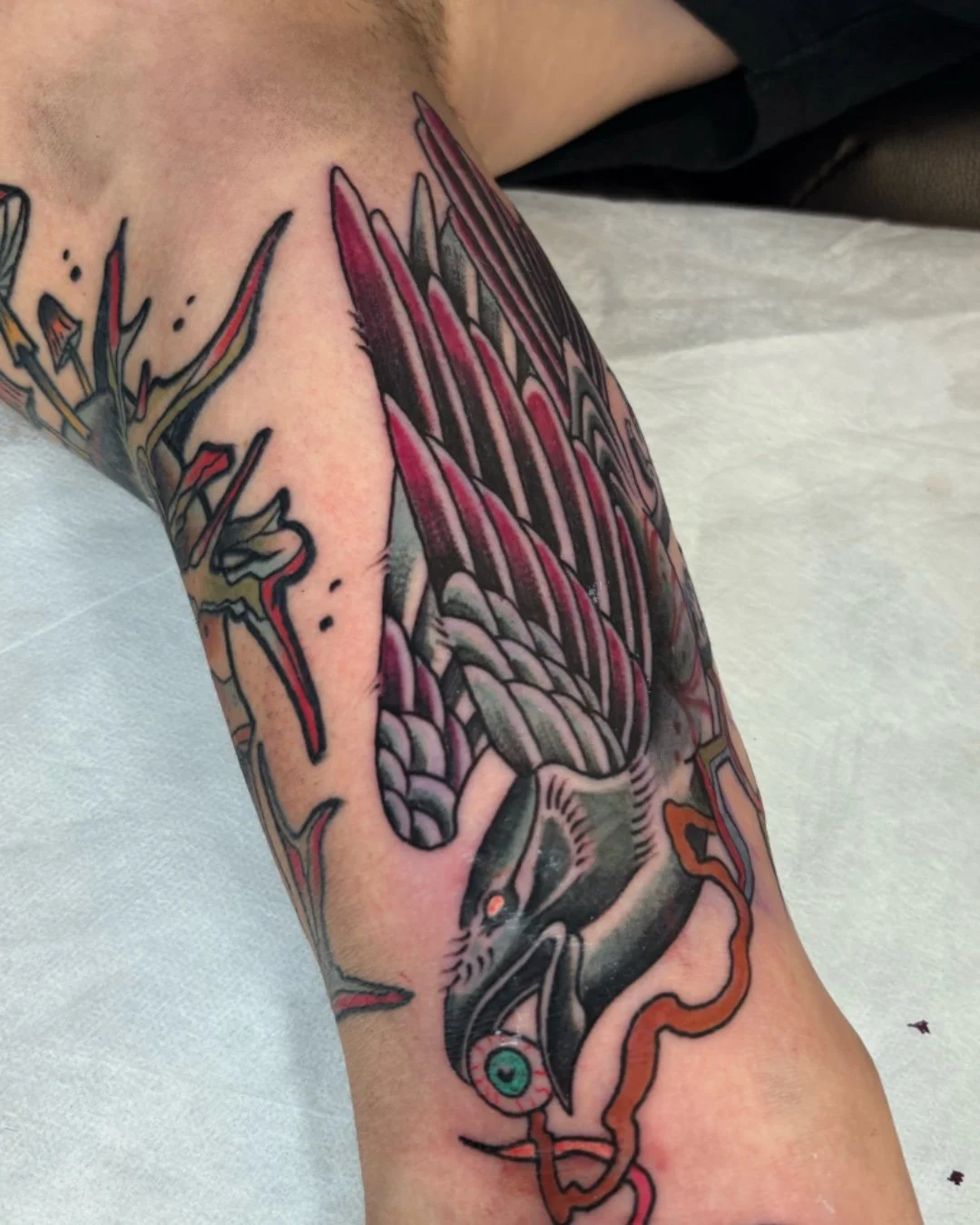 Neo-traditional raven tattoo created in West Palm Beach, Florida. This custom raven tattoo blends bold linework, rich color contrast, and modern illustrative details, staying true to neo-traditional tattoo aesthetics. The design highlights the raven’