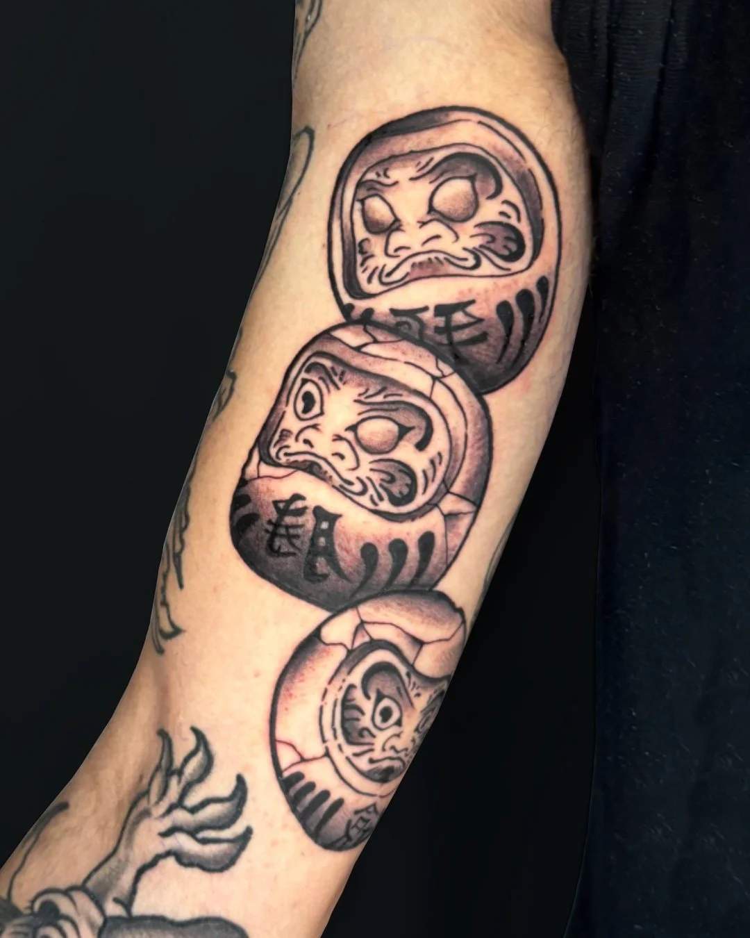 Traditional Japanese Daruma tattoo done in West Palm Beach, Florida. This custom tattoo features three Daruma dolls stacked in a vertical composition, inspired by classic Japanese tattoo tradition. Created with bold outlines, strong contrast, and sol