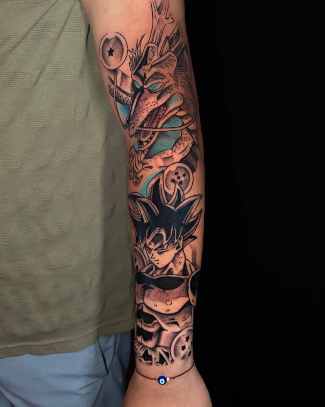 Dragon Ball anime tattoo featuring Shenron and Goku, tattooed in West Palm Beach, Florida. This custom black and grey anime sleeve combines the powerful presence of Shenron with an intense portrait of Goku, using bold linework, dotwork shading, and s