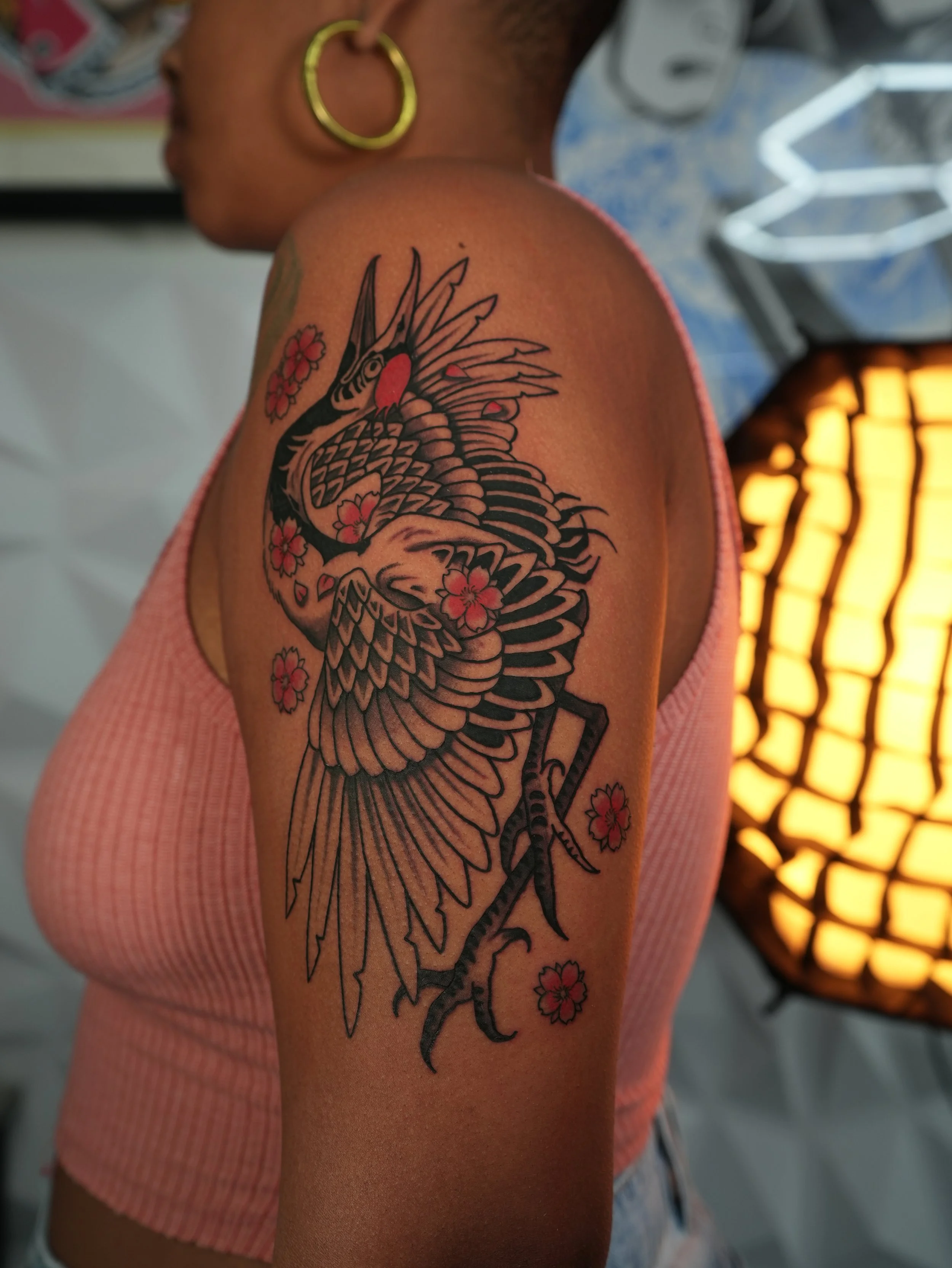 Traditional Japanese crane tattoo featuring cherry blossoms, bold linework, and black and grey shading with red accents. Custom tattoo by Yonathan Suarez, a traditional and illustrative tattoo artist in West Palm Beach, Florida.