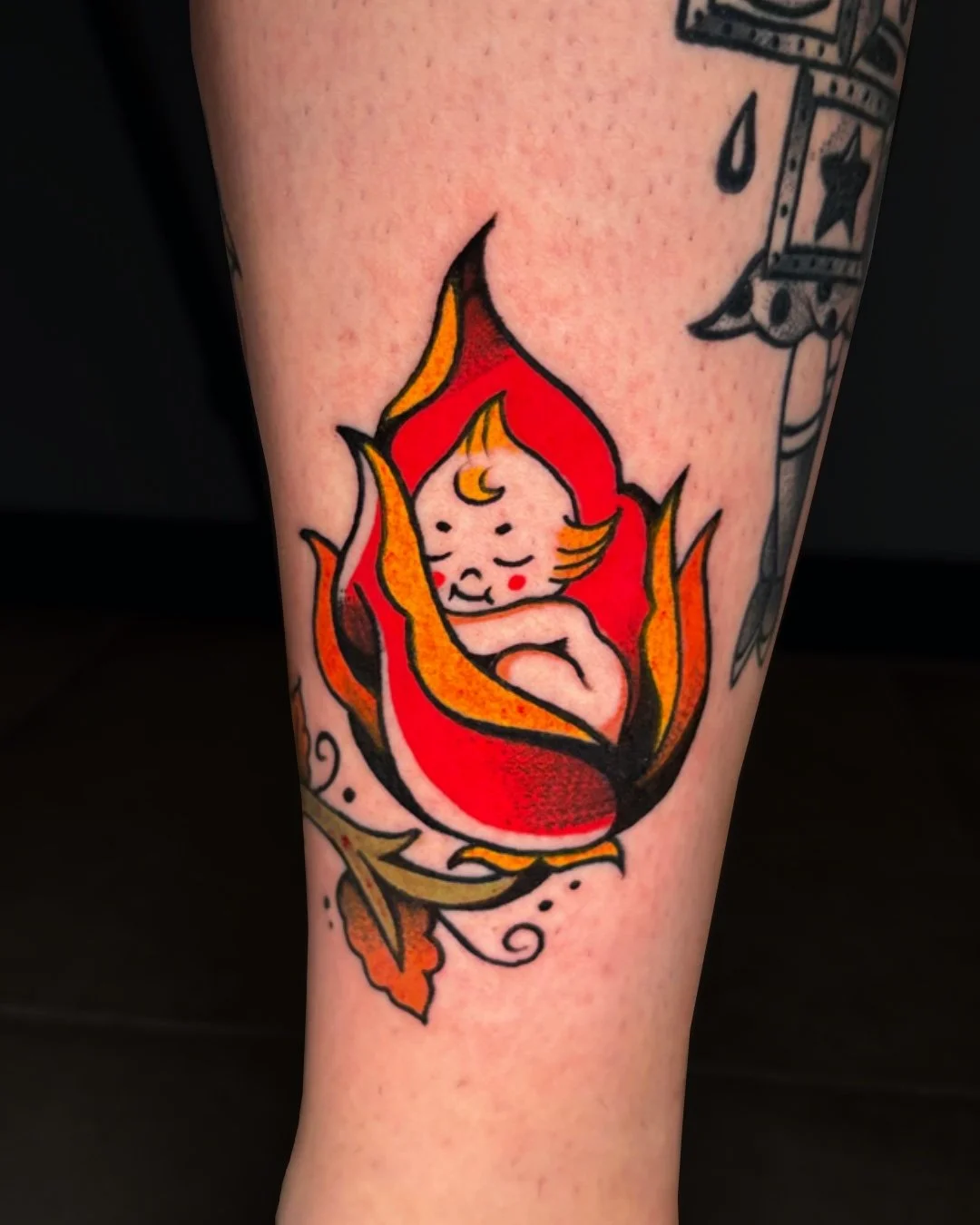American traditional Kewpie tattoo done in West Palm Beach, Florida. This custom tattoo features a classic Kewpie doll inspired by vintage American traditional tattoo art, with bold outlines, warm color tones, and strong contrast. The flame compositi