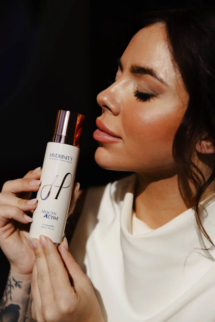 Model holding a skincare bottle against a black background
