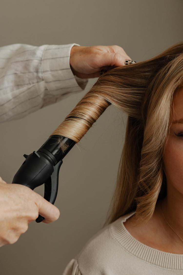 Stylist curling a client's hair