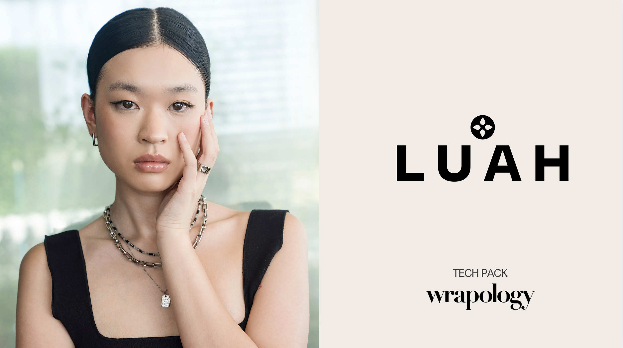 A woman with dark hair touching her face, wearing a black top and jewelry, standing near a window. Next to her, there is text that reads "LUAH," with a small design above the last letter, and below it, "TECH PACK wrapology" on a light background.