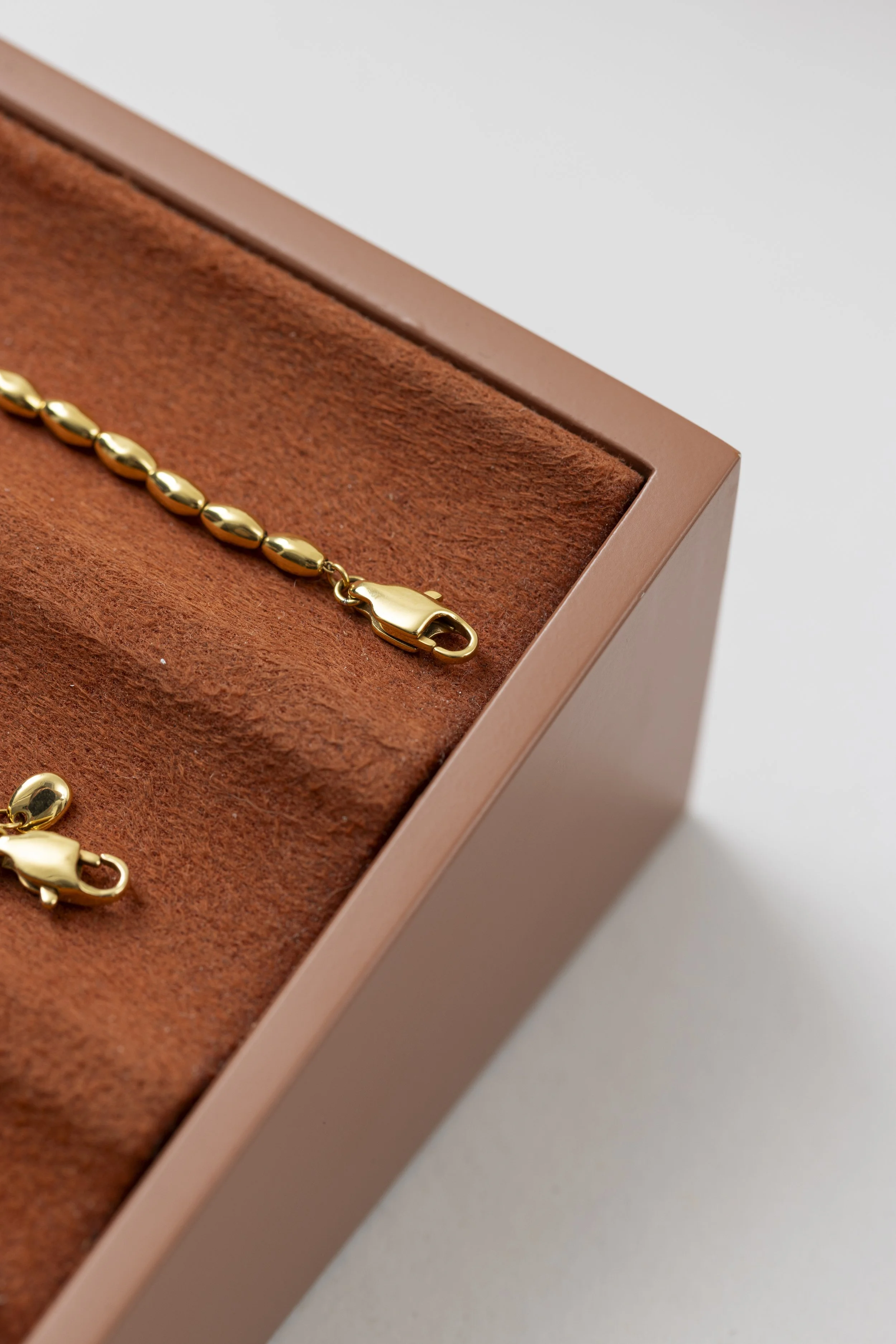 Close-up of a gold jewelry clasp on a necklace resting on a  suede jewelry display