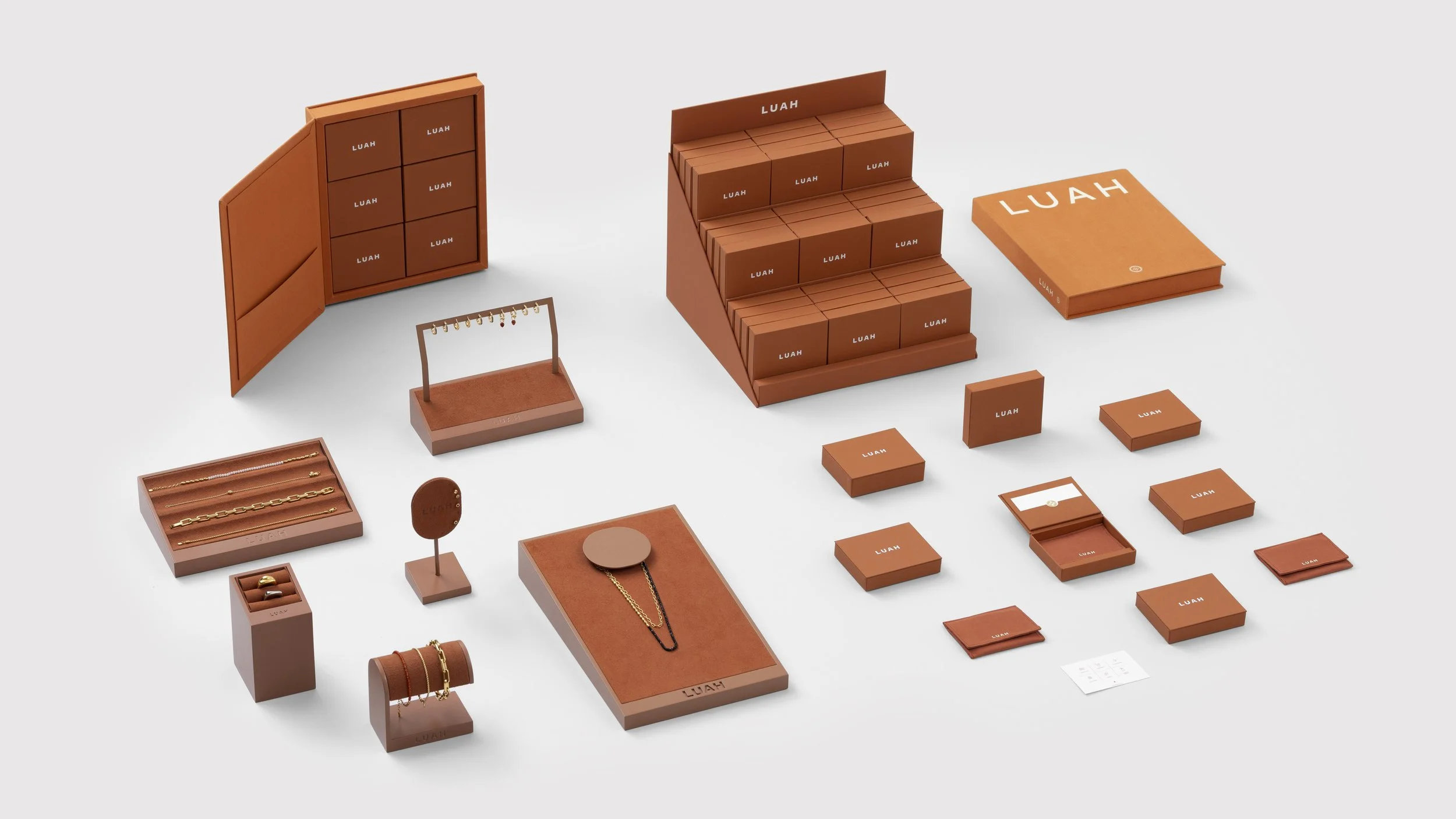 Display of jewelry and accessories with orange packaging and display stands, including necklaces, rings, bracelets, and cardholders, all labeled 'LUAH'.