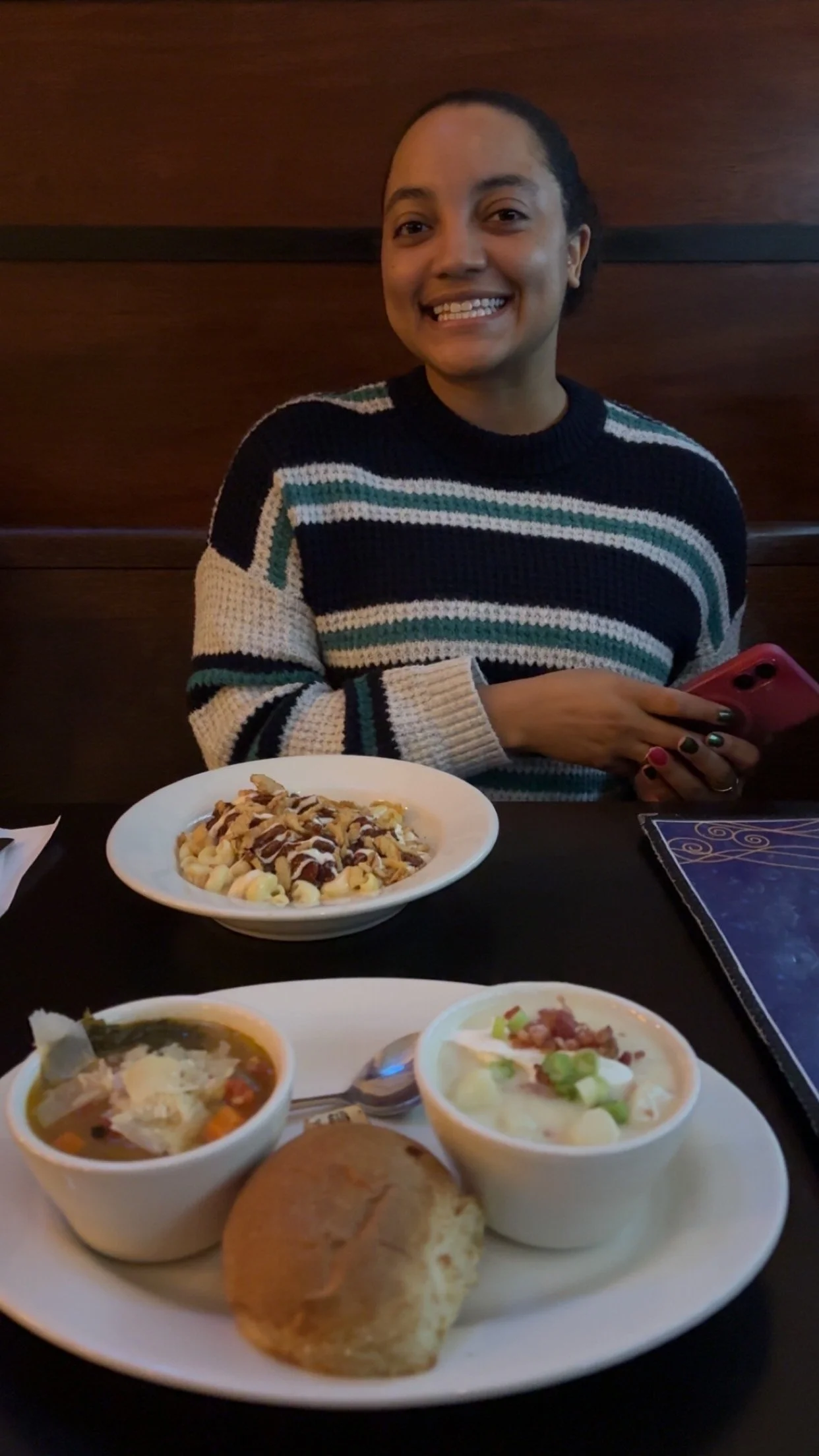 Samantha wearing a sweater, smiling over a plate of food