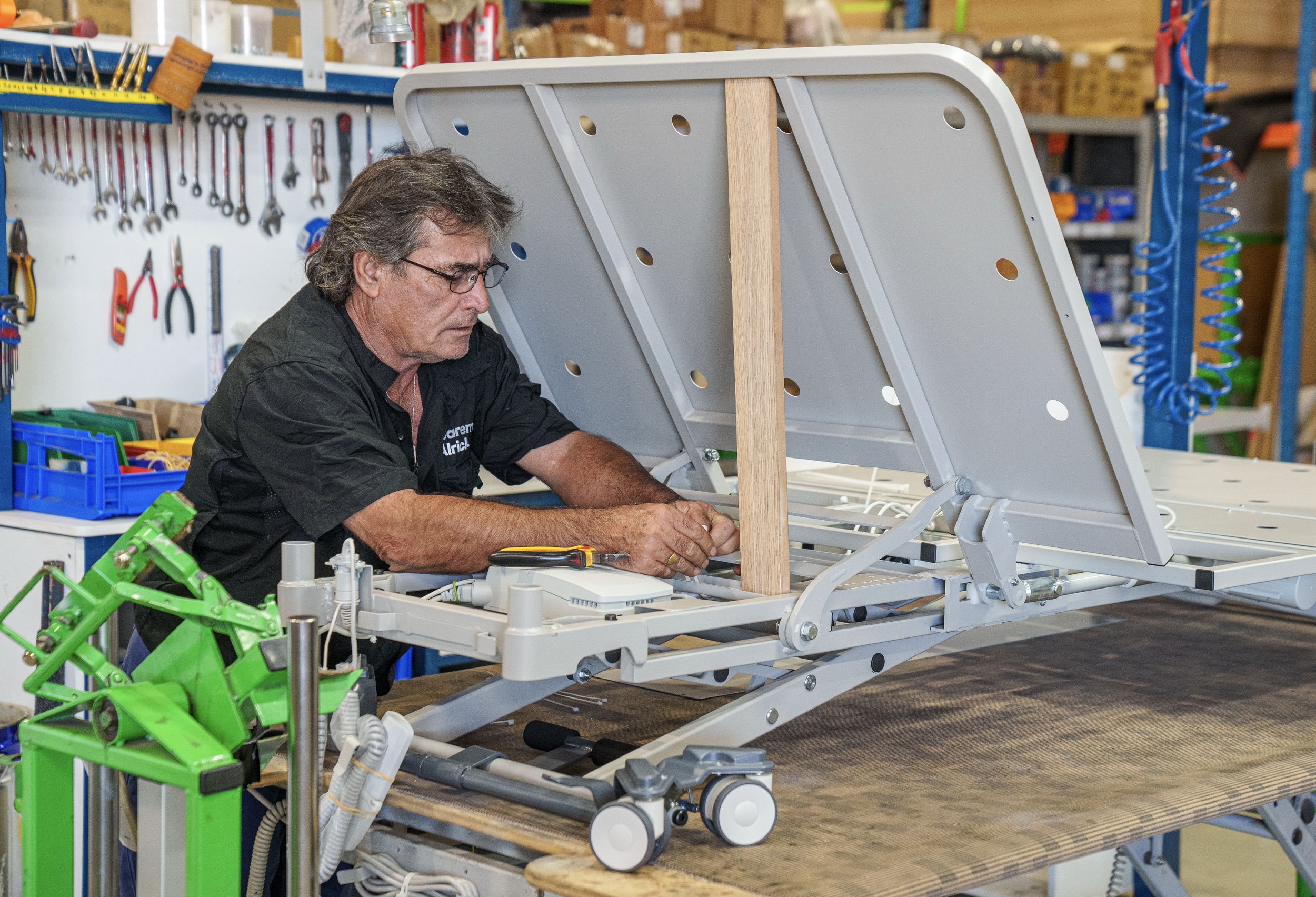 A man working on assembling a medical bed in a workshop.