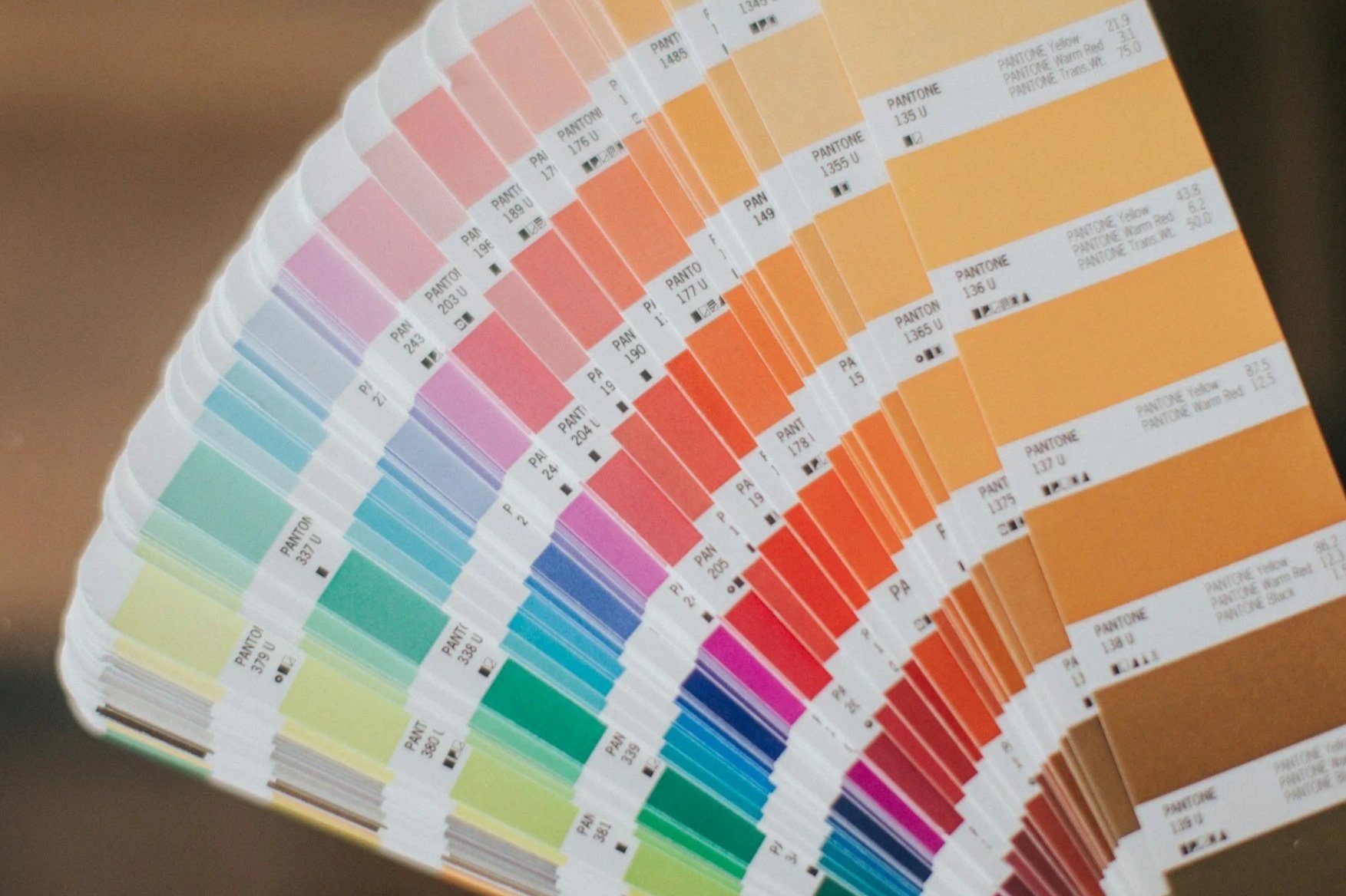 Color swatch fan deck displaying Pantone color samples arranged in a gradient from pastel pinks and purples to vibrant blues, greens, yellows, and oranges.