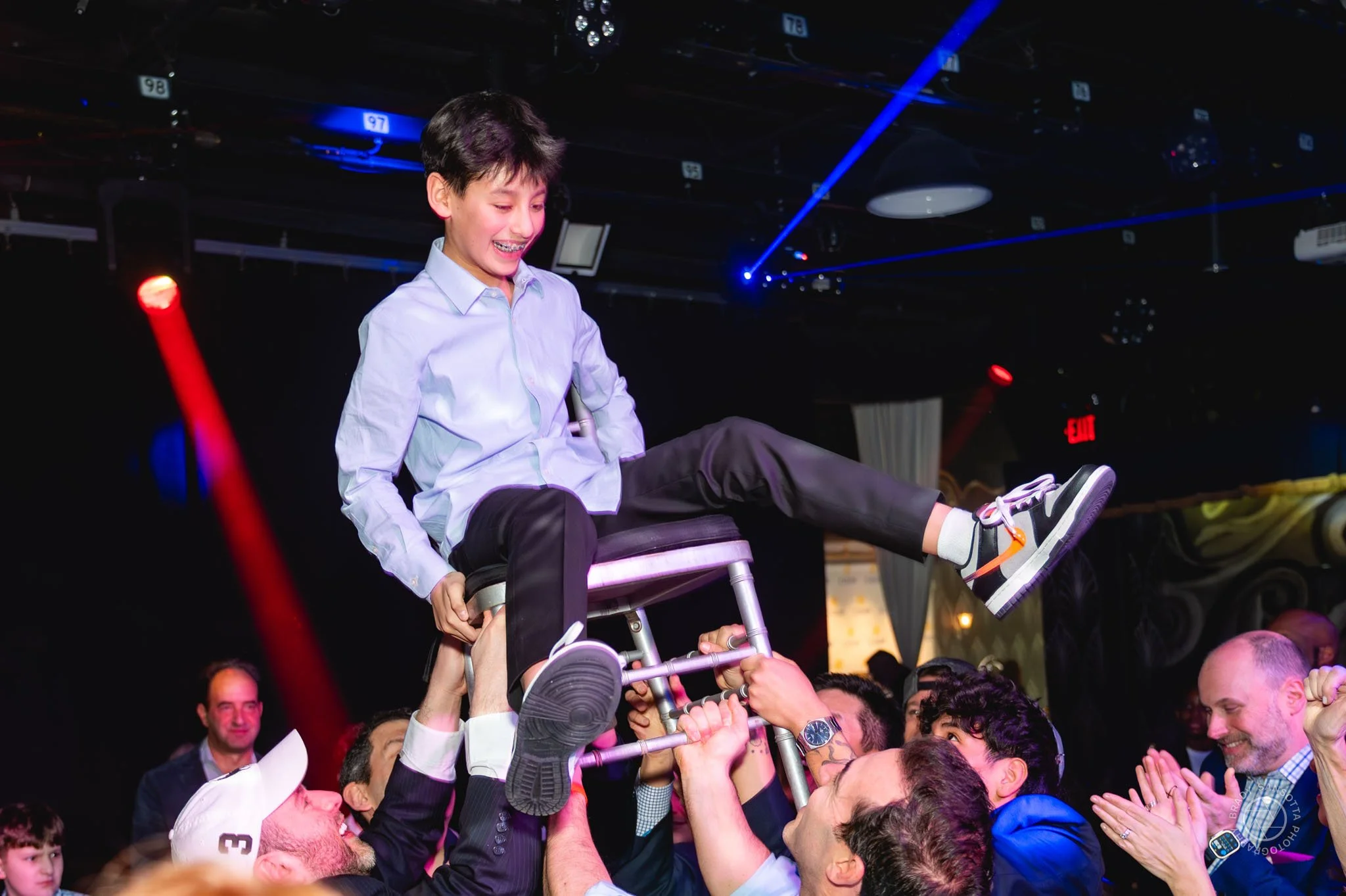 Bar Mitzvah boy lifted in chair for the Hora. Candid dance floor photography at Powerhouse Studios Paramus.