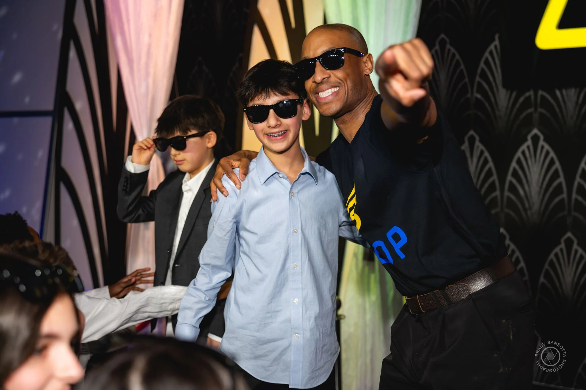 Posed photograph with bar mitzvah boy and emcee during party in Paramus, New Jersey.