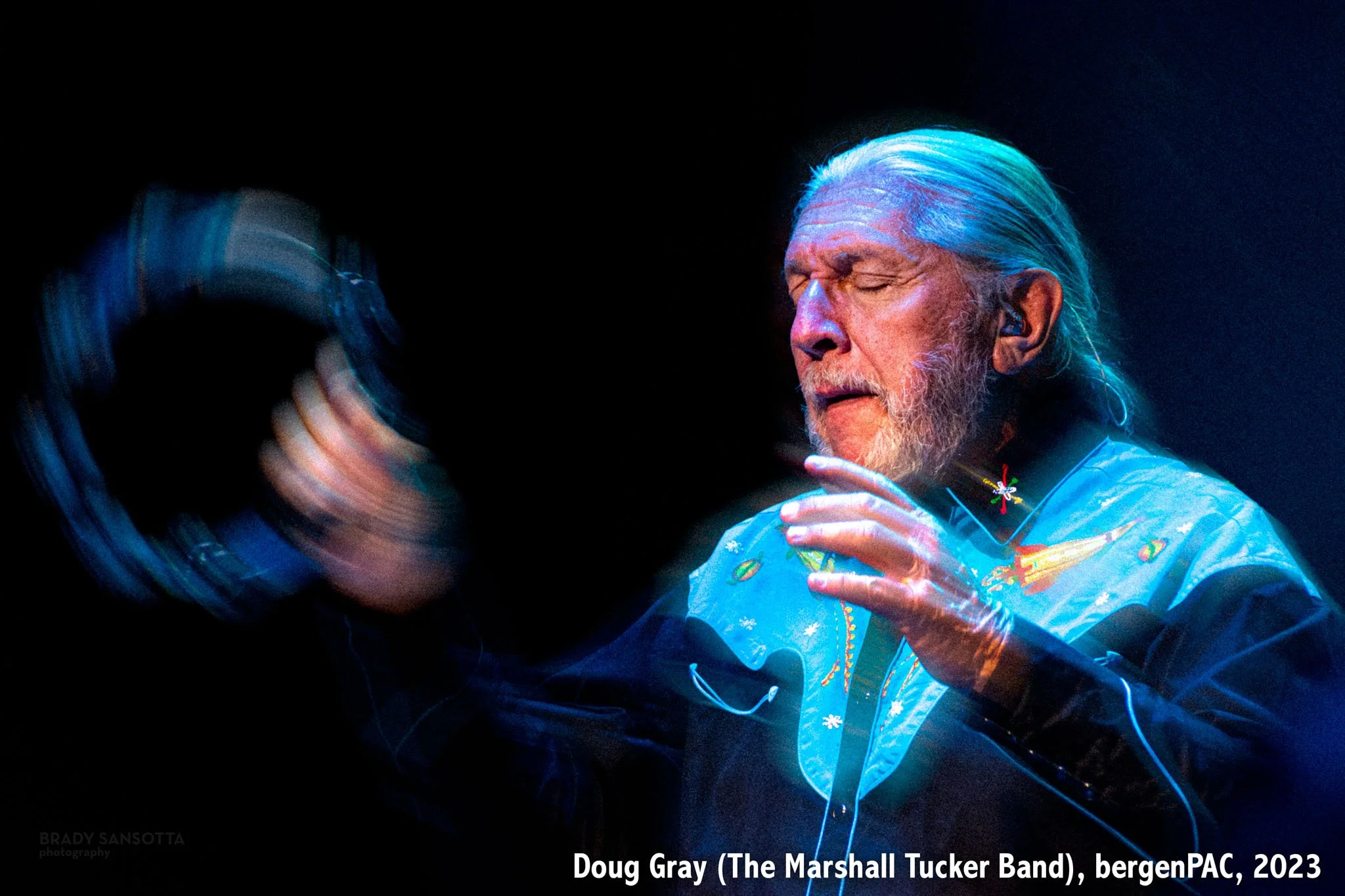 Doug Gray of The Marshall Tucker Band playing tambourine during a southern rock performance at BergenPAC.