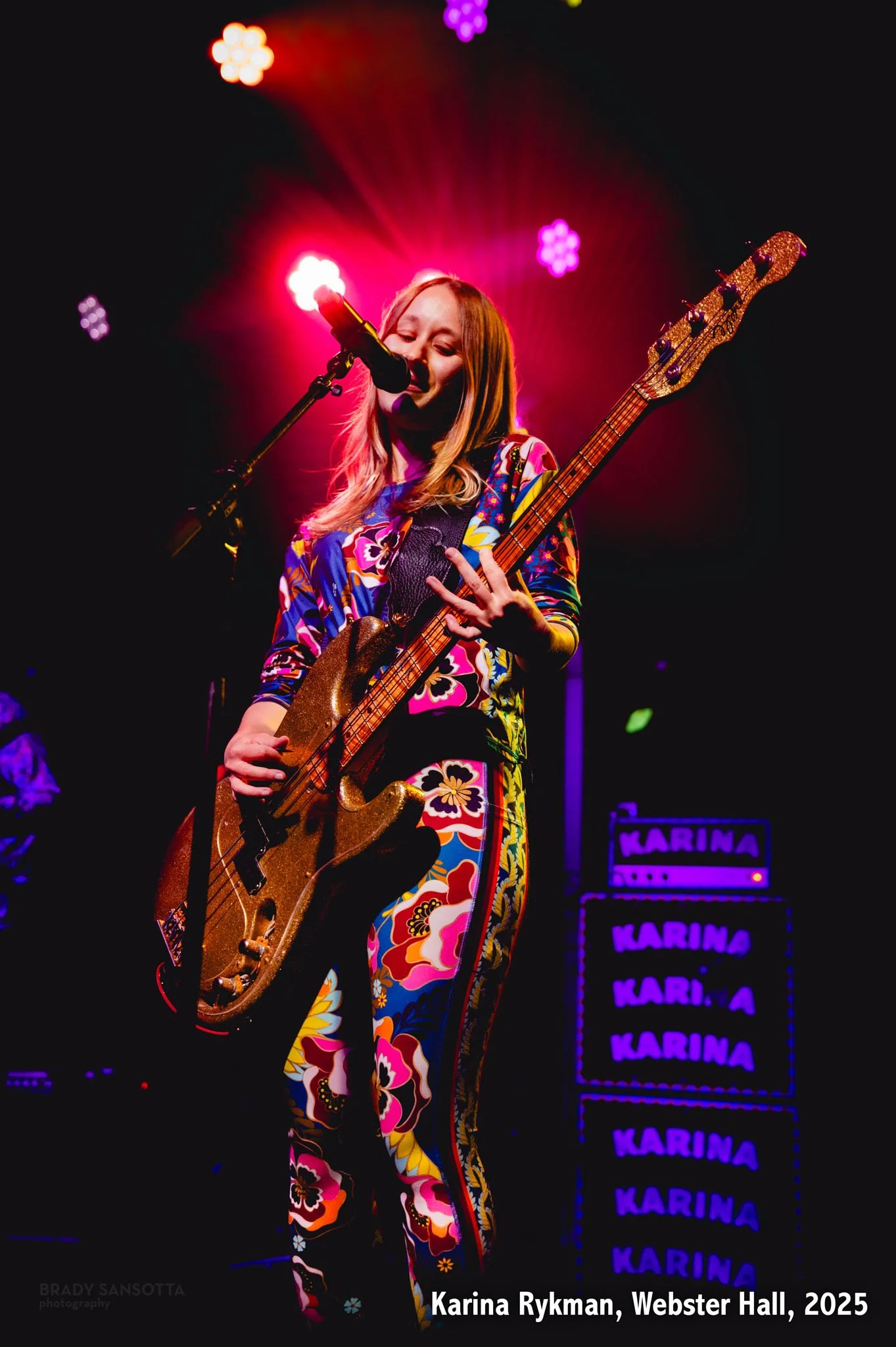 Karina Rykman performing live with bass guitar and red backlight at Webster Hall in New York City.