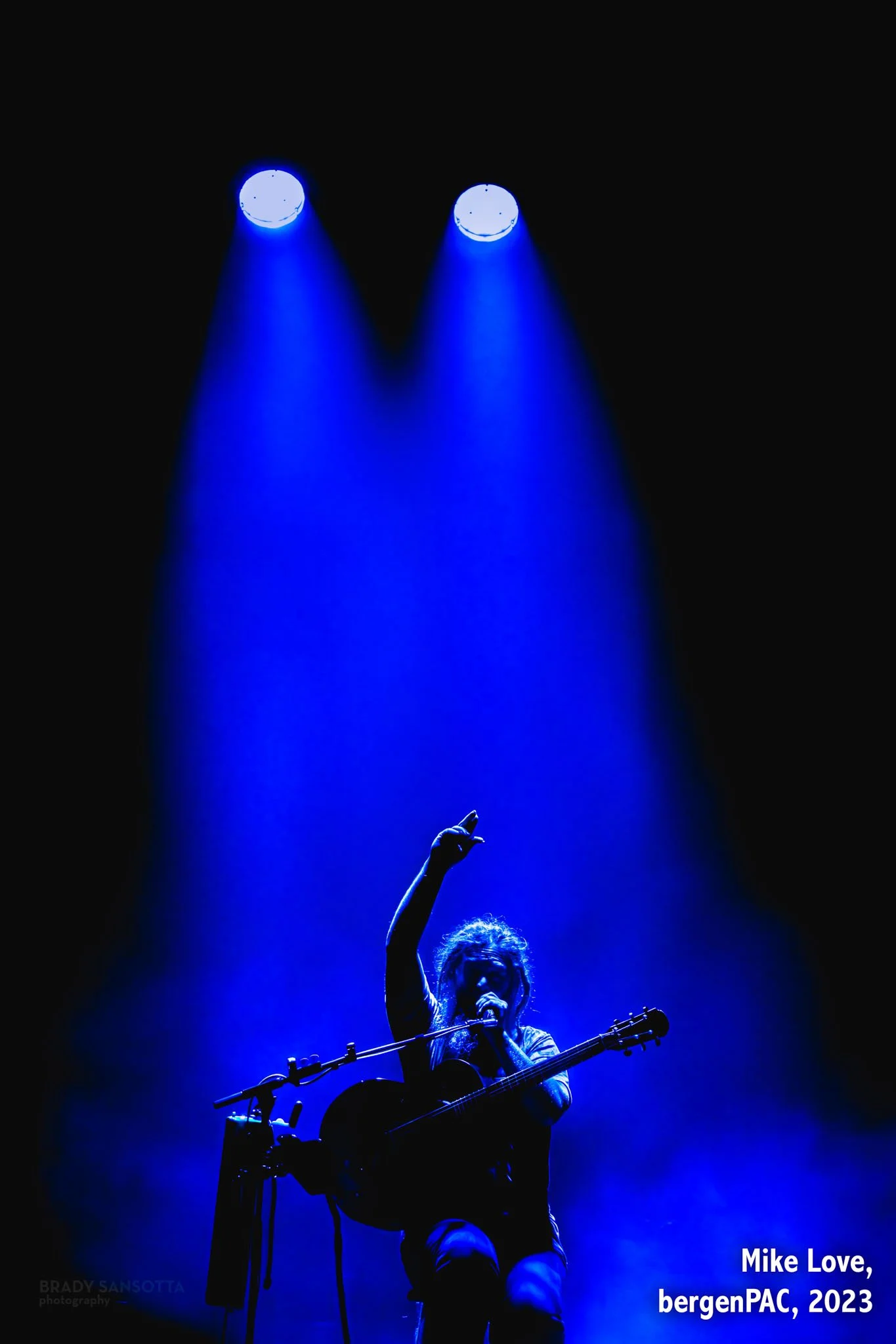 Silhouetted portrait of reggae singer Mike Love performing under vivid blue stage lights at BergenPAC in Englewood, NJ.