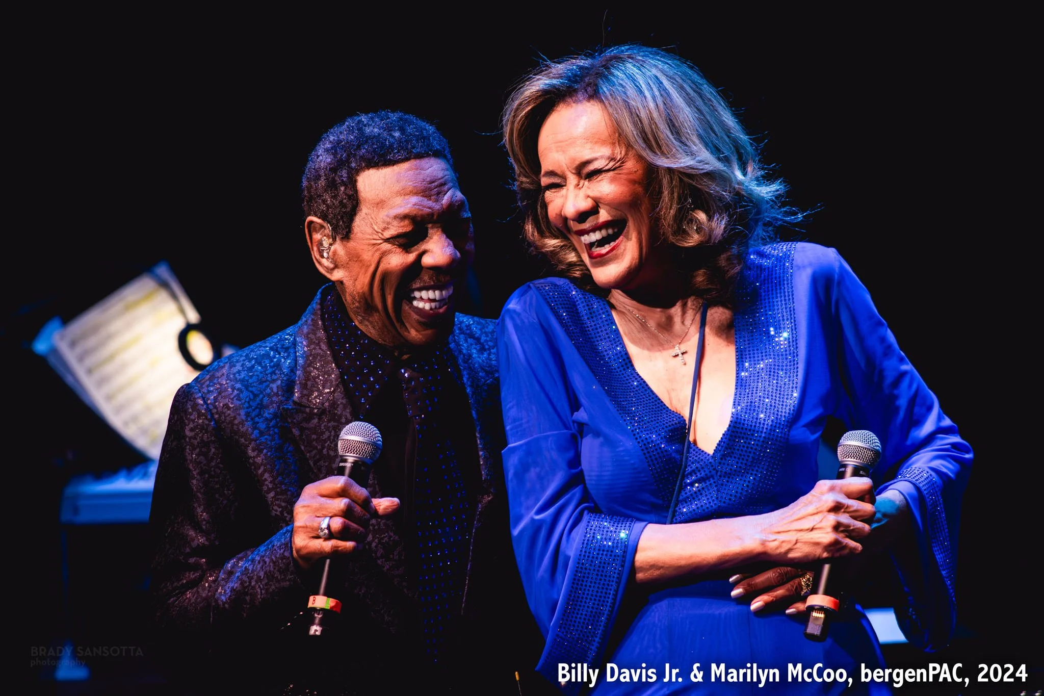 Marilyn McCoo and Billy Davis Jr. smiling and singing together during a live show at BergenPAC in Englewood, NJ.