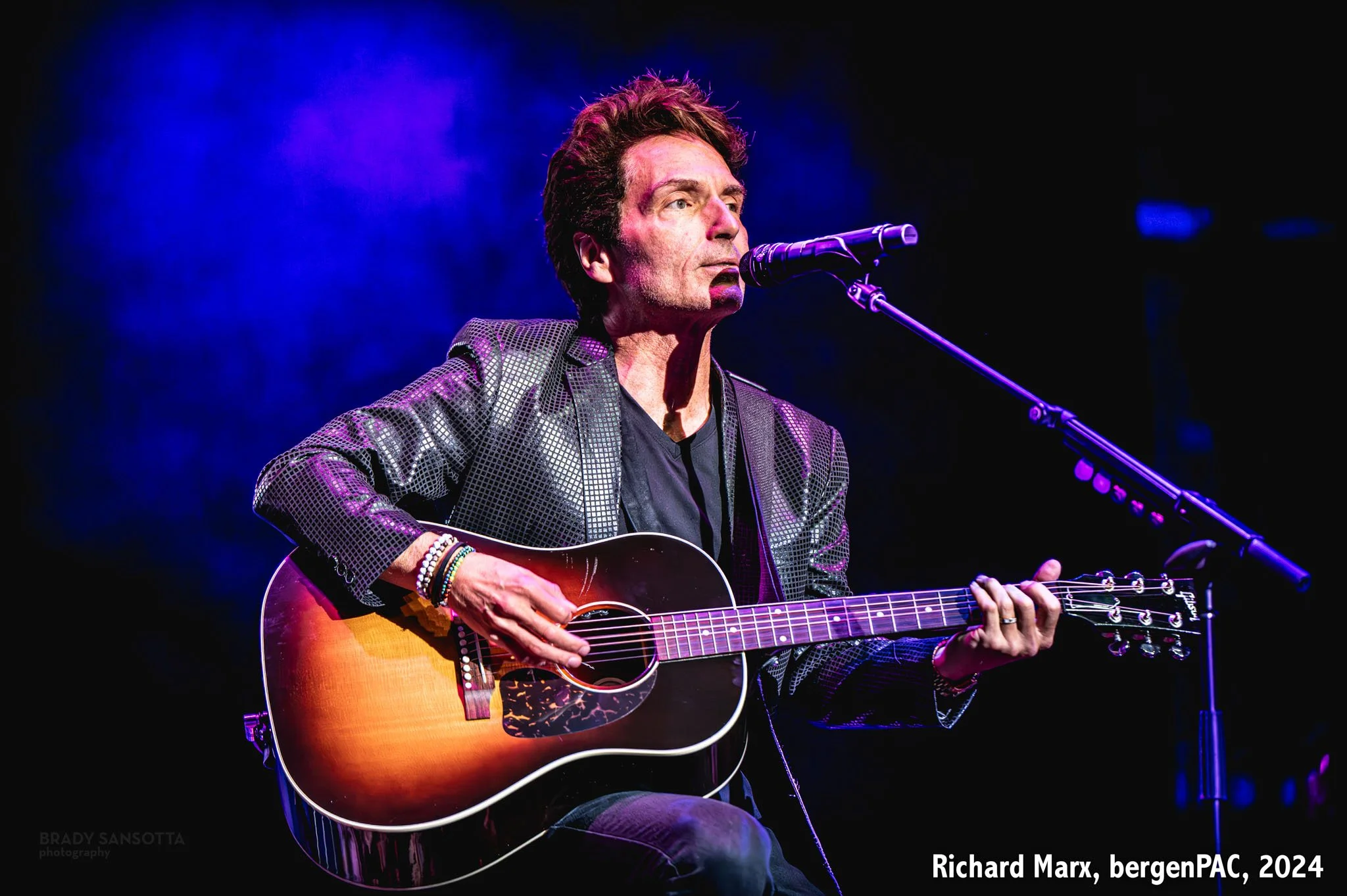 Richard Marx singing and playing guitar surrounded by dramatic blue fog at BergenPAC in Englewood, NJ.