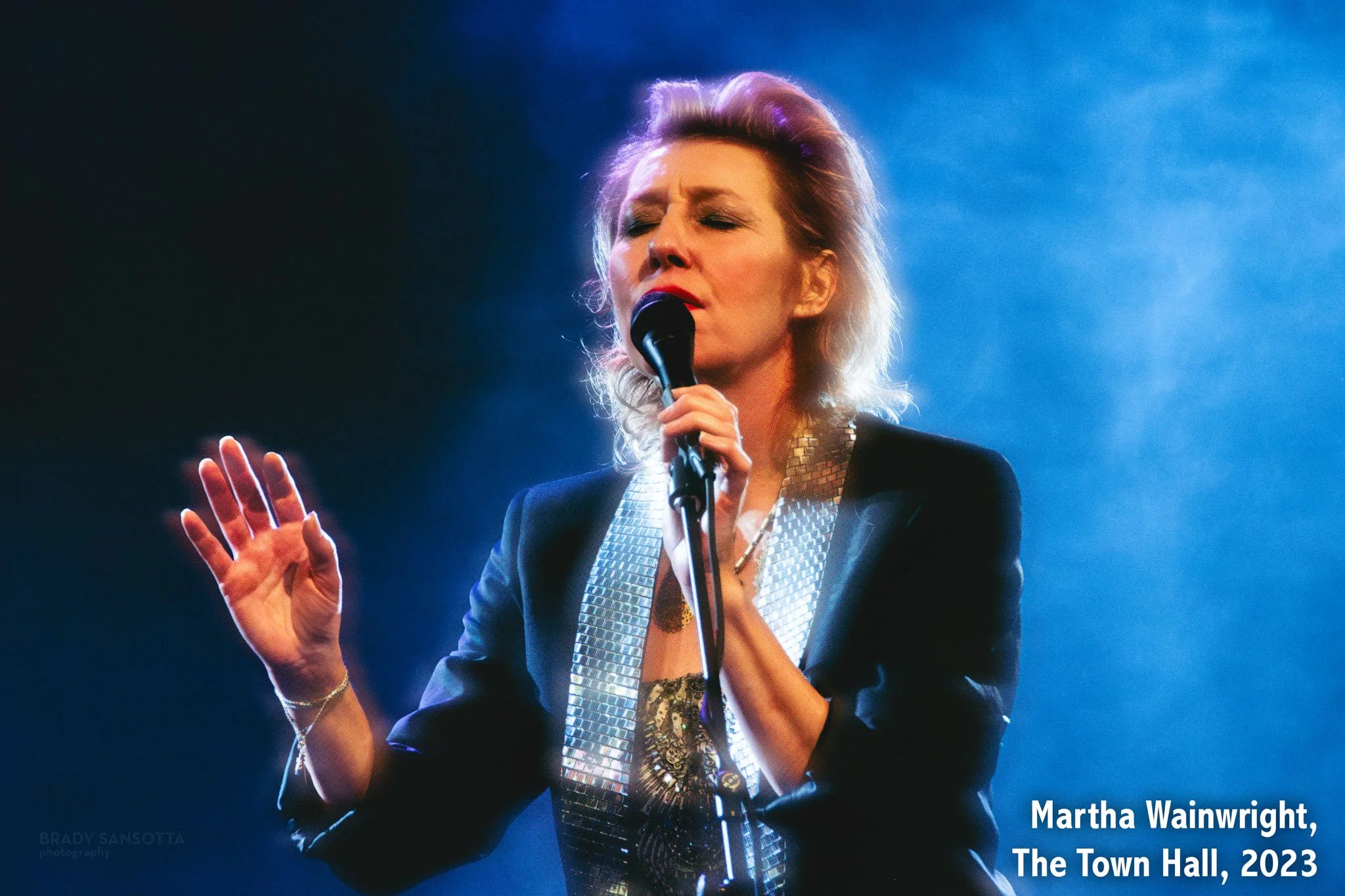 Martha Wainwright singing under moody blue fog at the "A Not So Silent Night" concert at Town Hall in New York City.