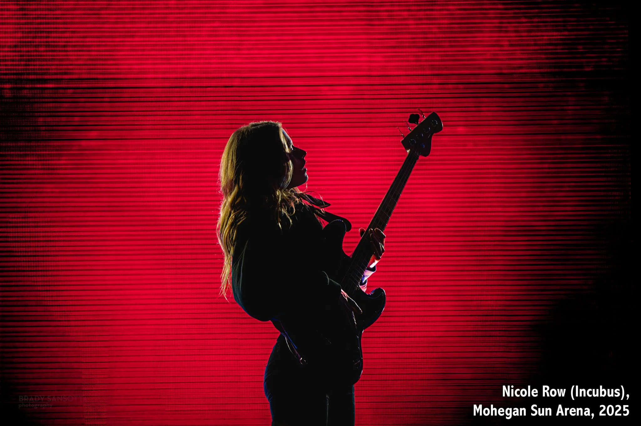 Dramatic portrait of bassist Nicole Row of Incubus (and Panic! at the Disco) performing live at Mohegan Sun Arena.