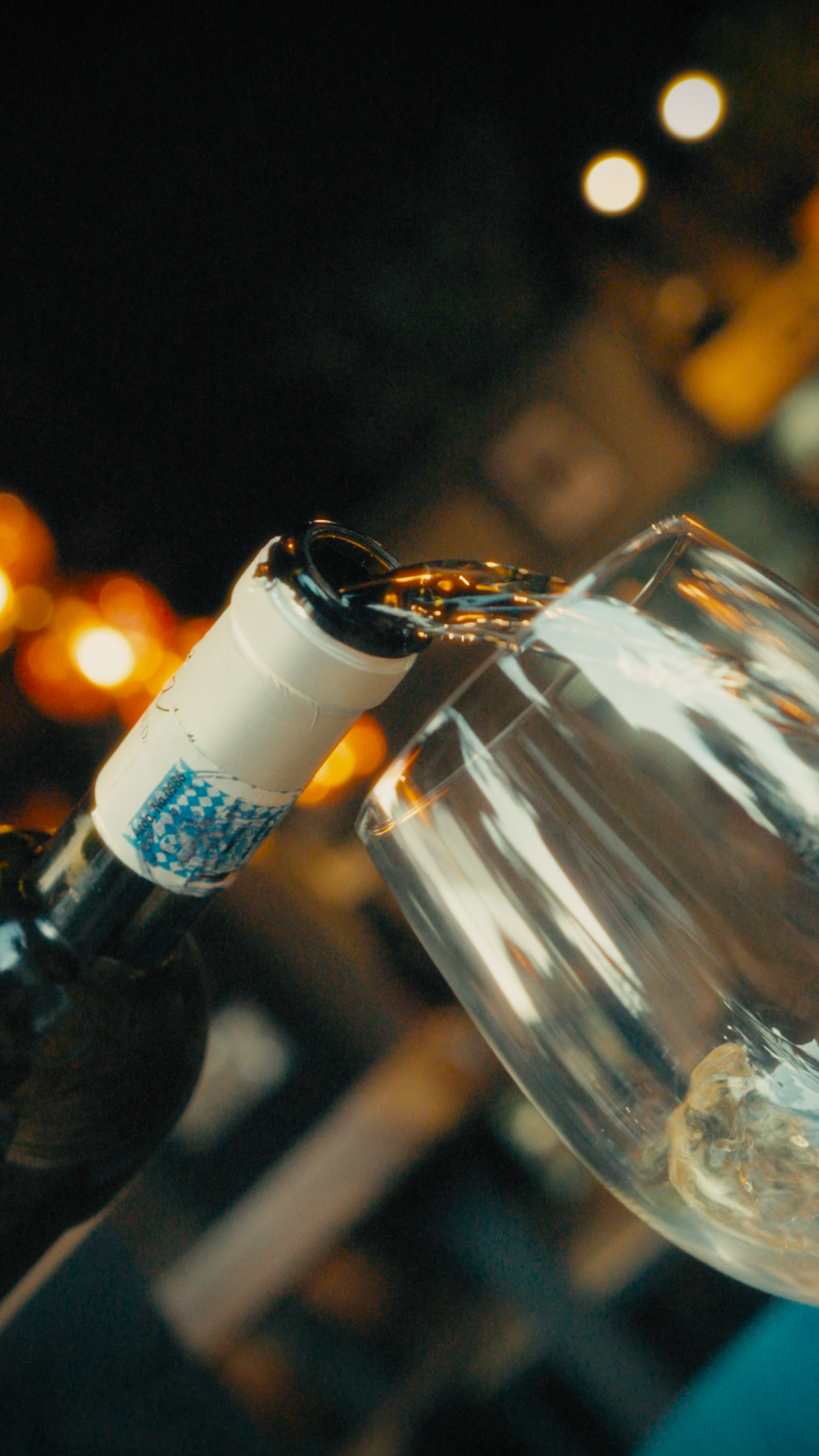 A close-up of a bottle of white wine being poured into a wine glass.