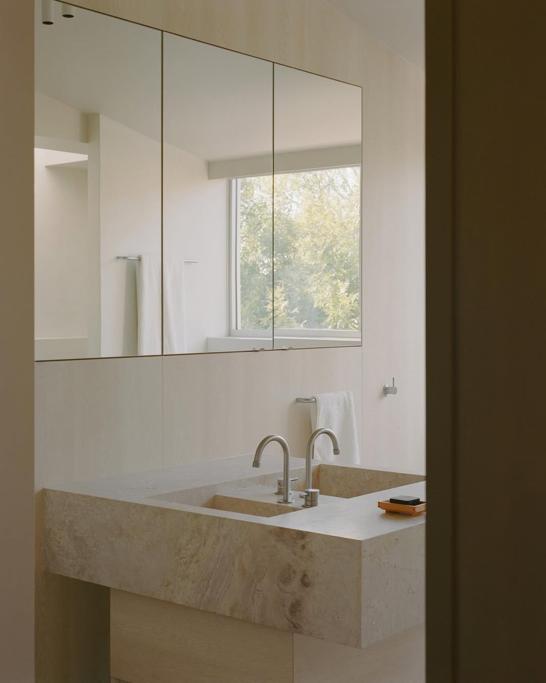 light filled bathroom with microcement walls and custom marble joinery