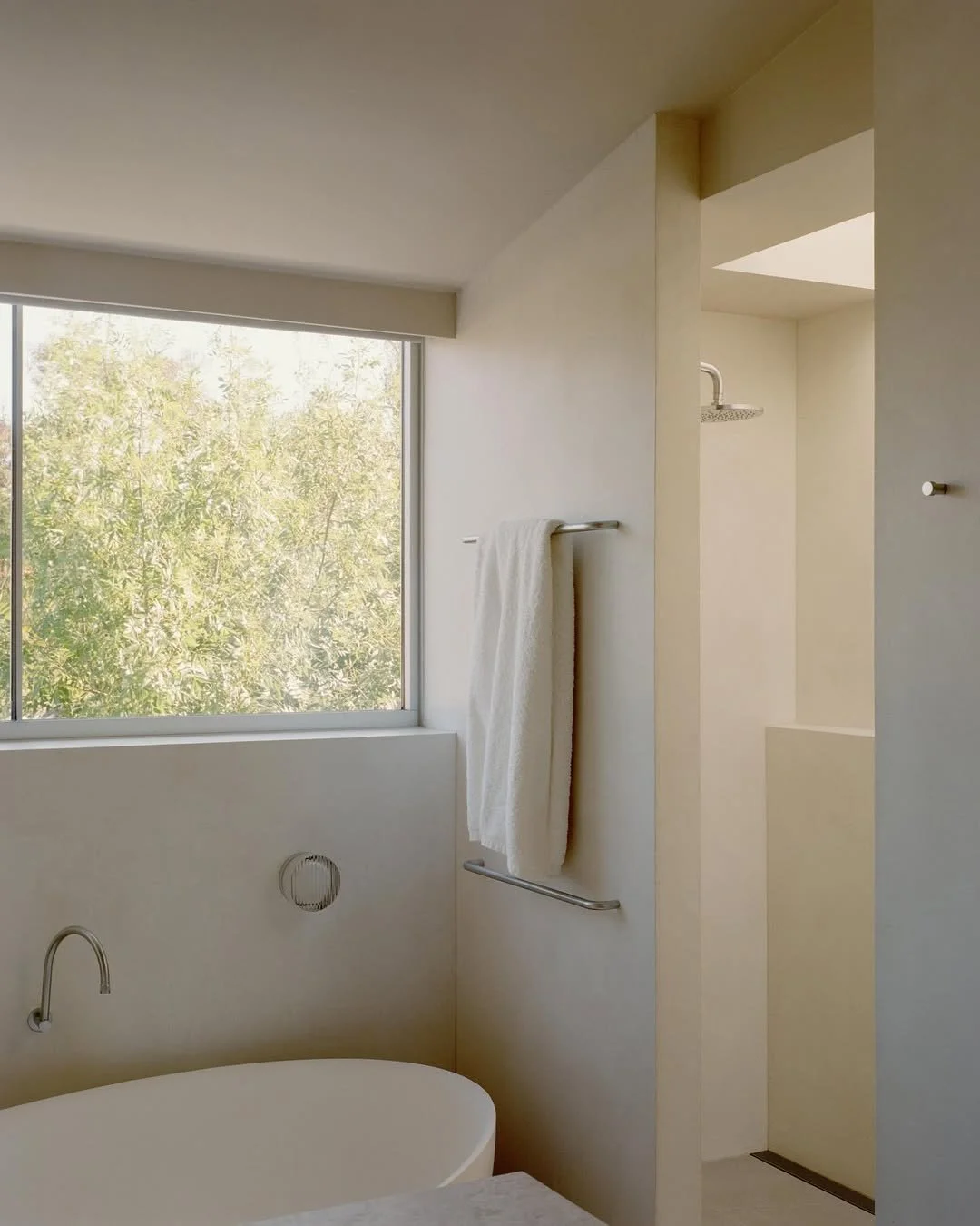 light filled bathroom with xbond microcement walls and lush garden outside