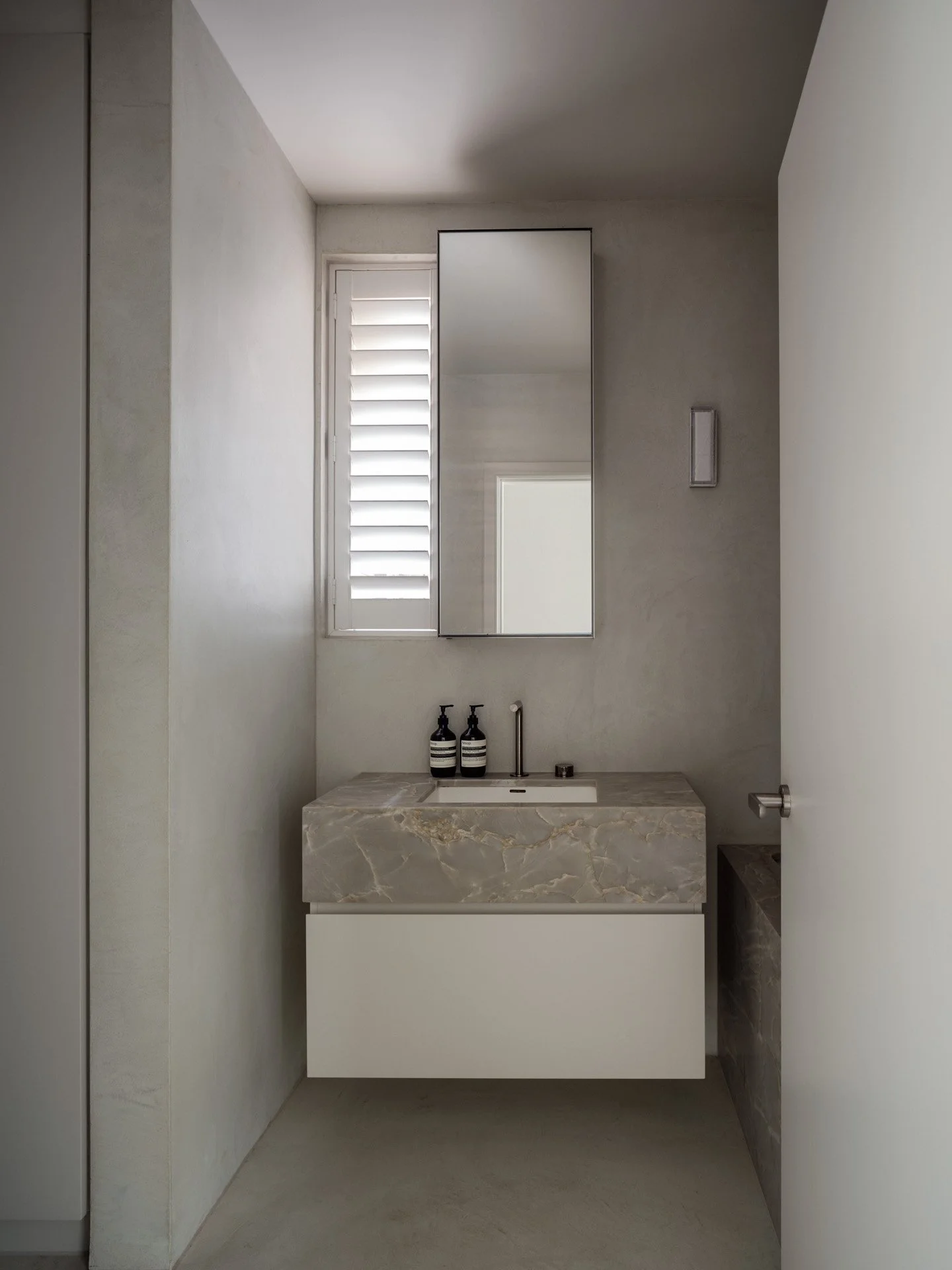 warm toned bathroom with microcement walls and statement stone joinery