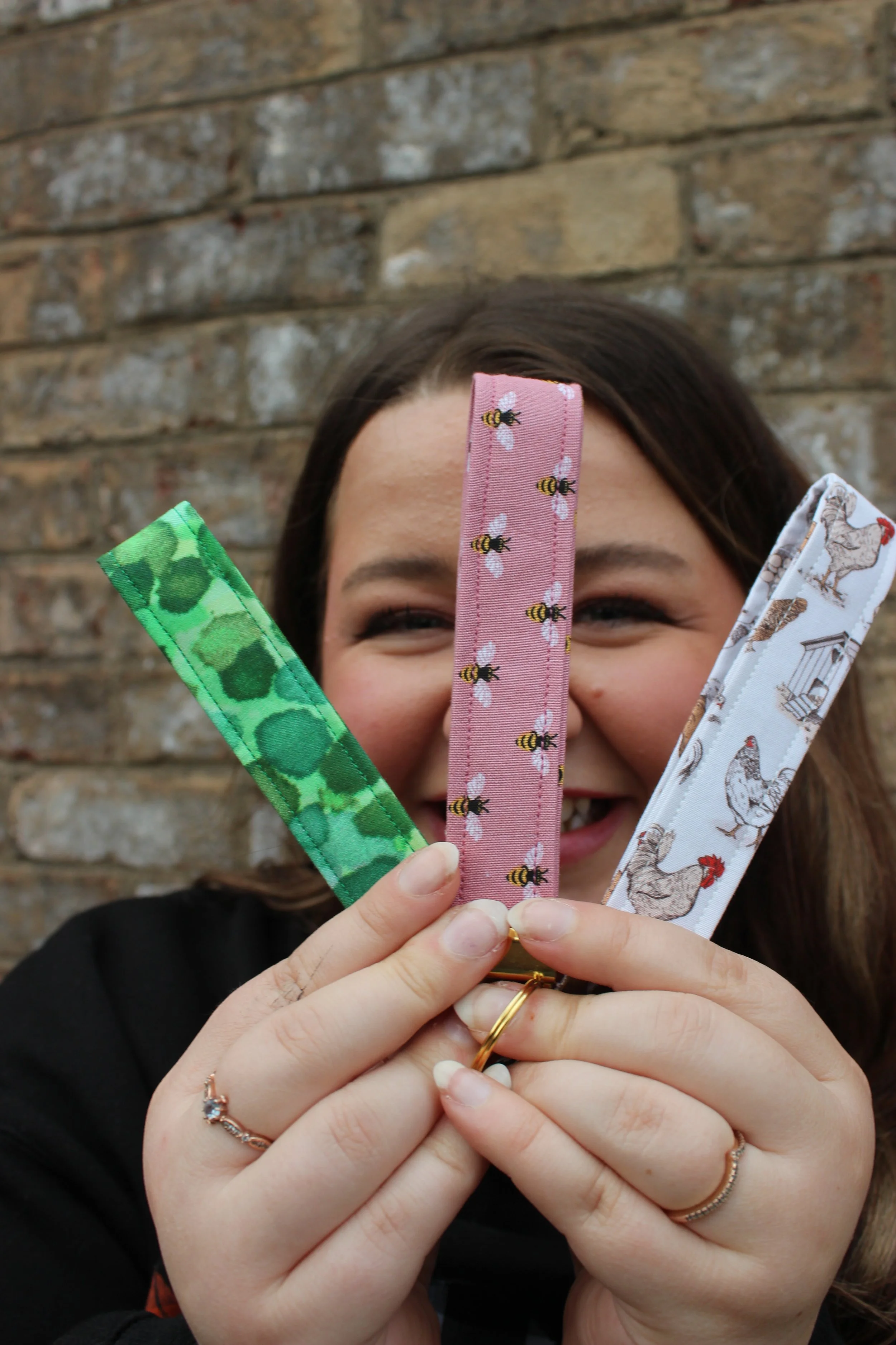 Angelina smiling while holding three handmade keychains
