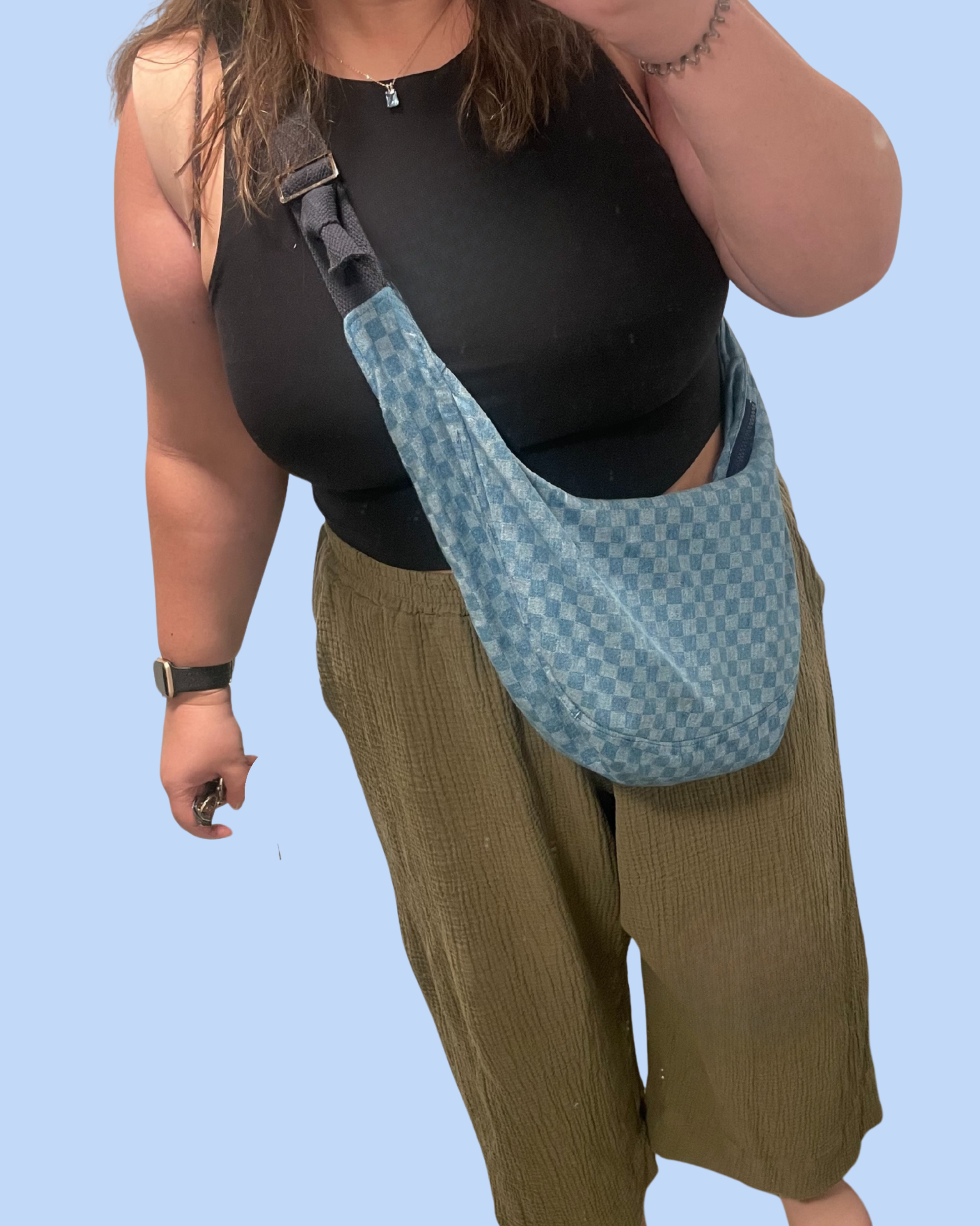 Woman modeling green pants and a checkered crossbody bag