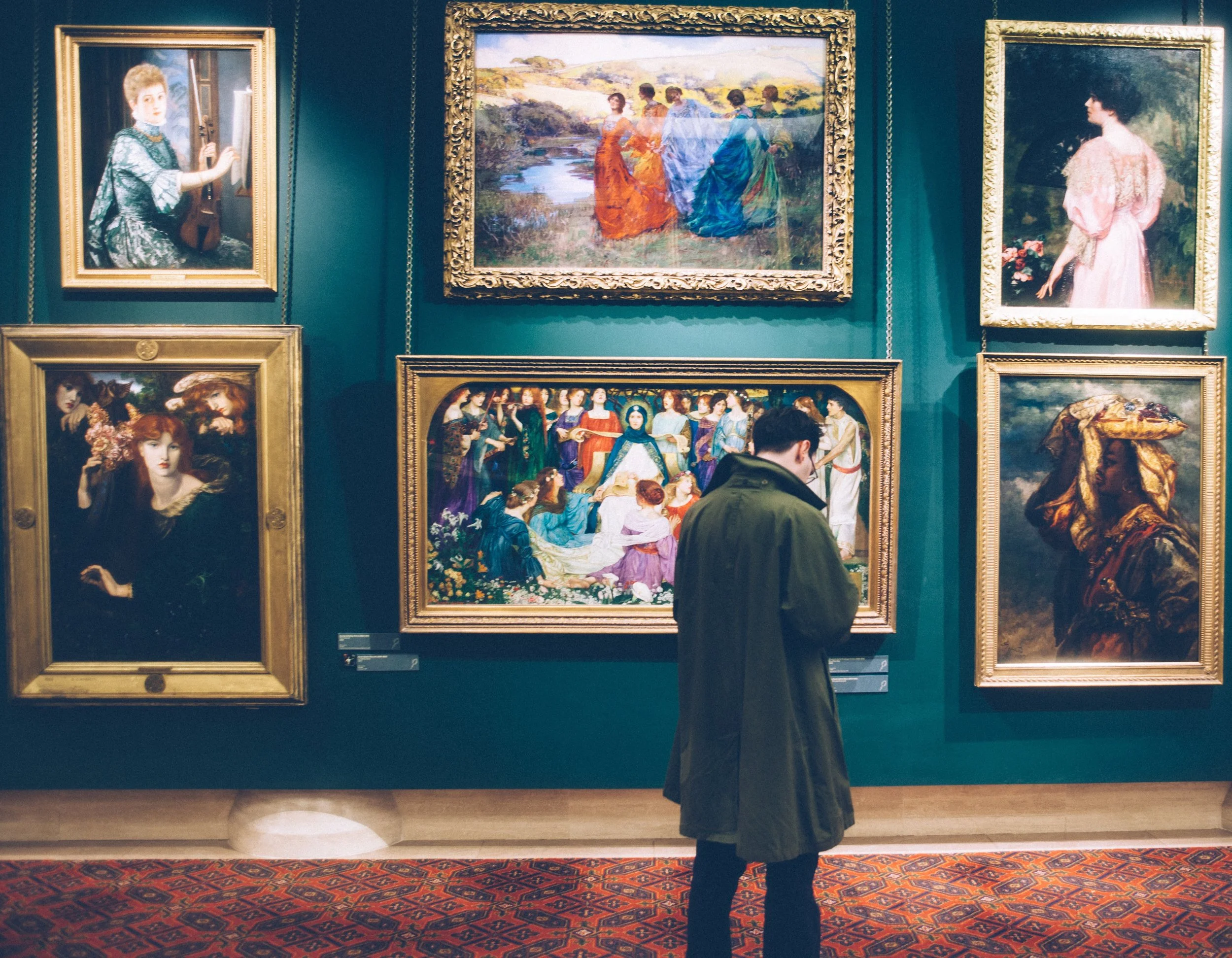 Visitor observing framed classical paintings in a museum gallery