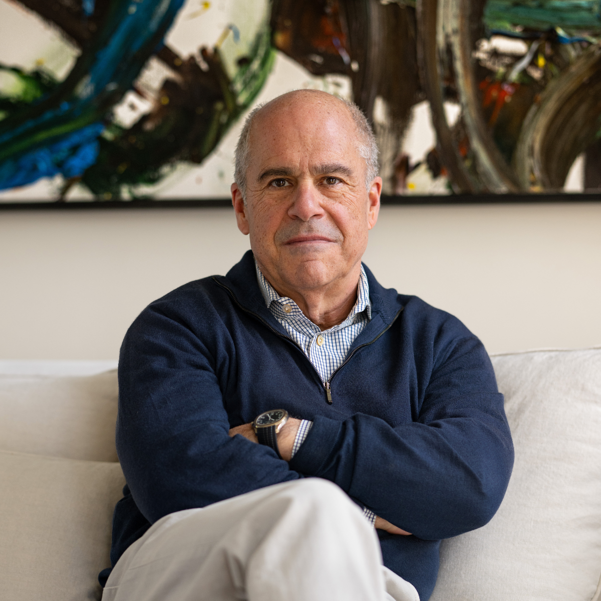 Jeff Greenstein sitting in Velaras office.Behind him is an abstract painting with dark, blue, and earthy tones.