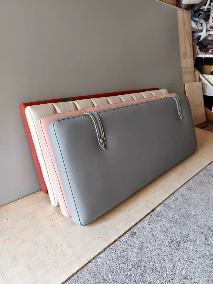 Colorful cushioned headboards and wall panels leaning against a gray wall on a wooden platform.
