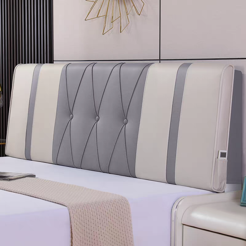 A modern bedroom headboard with gray and cream padded sections, a white bedspread, a knitted beige throw blanket, and a wall with gold geometric wall decor.