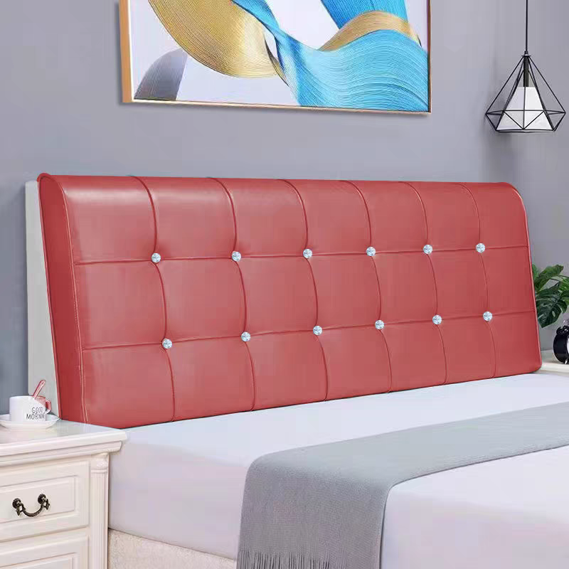 A bedroom with a taupe-colored wall, a large piece of abstract art, a geometric black wall sconce, a red upholstered headboard with button tufting, and a white nightstand with a coffee mug and spoon on top. There is also a green plant visible on the 