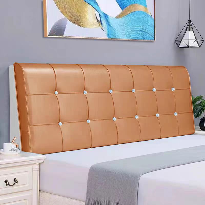 A bedroom with a tan upholstered headboard, a white nightstand, a white bed with a gray blanket, a modern geometric pendant light, a potted plant, and abstract artwork with blue, beige, and black colors on a gray wall.