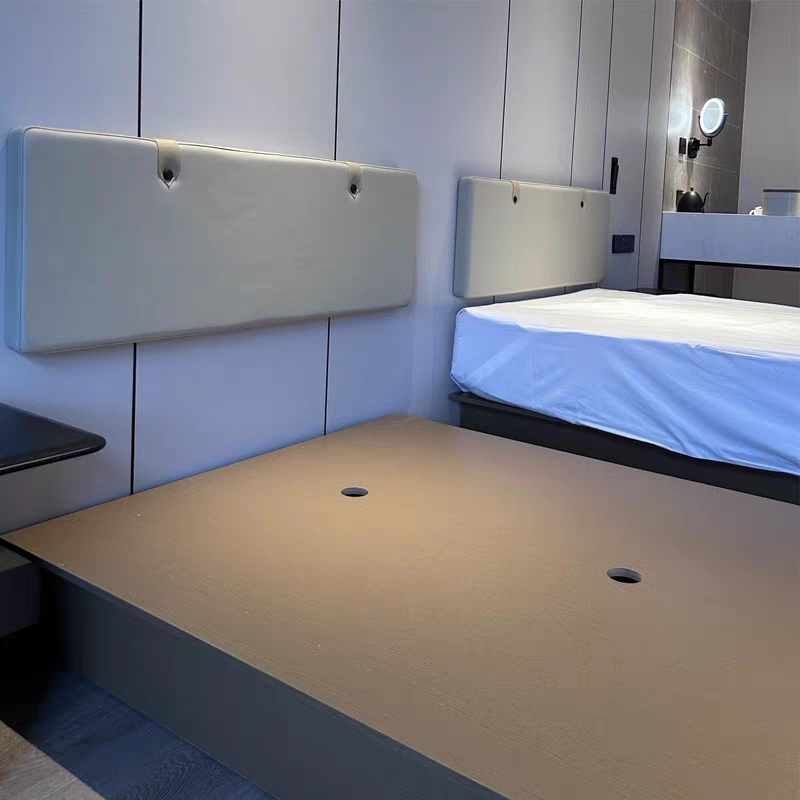Modern hotel room with a partially made bed, beige upholstered headboards, and a beige platform bed base.