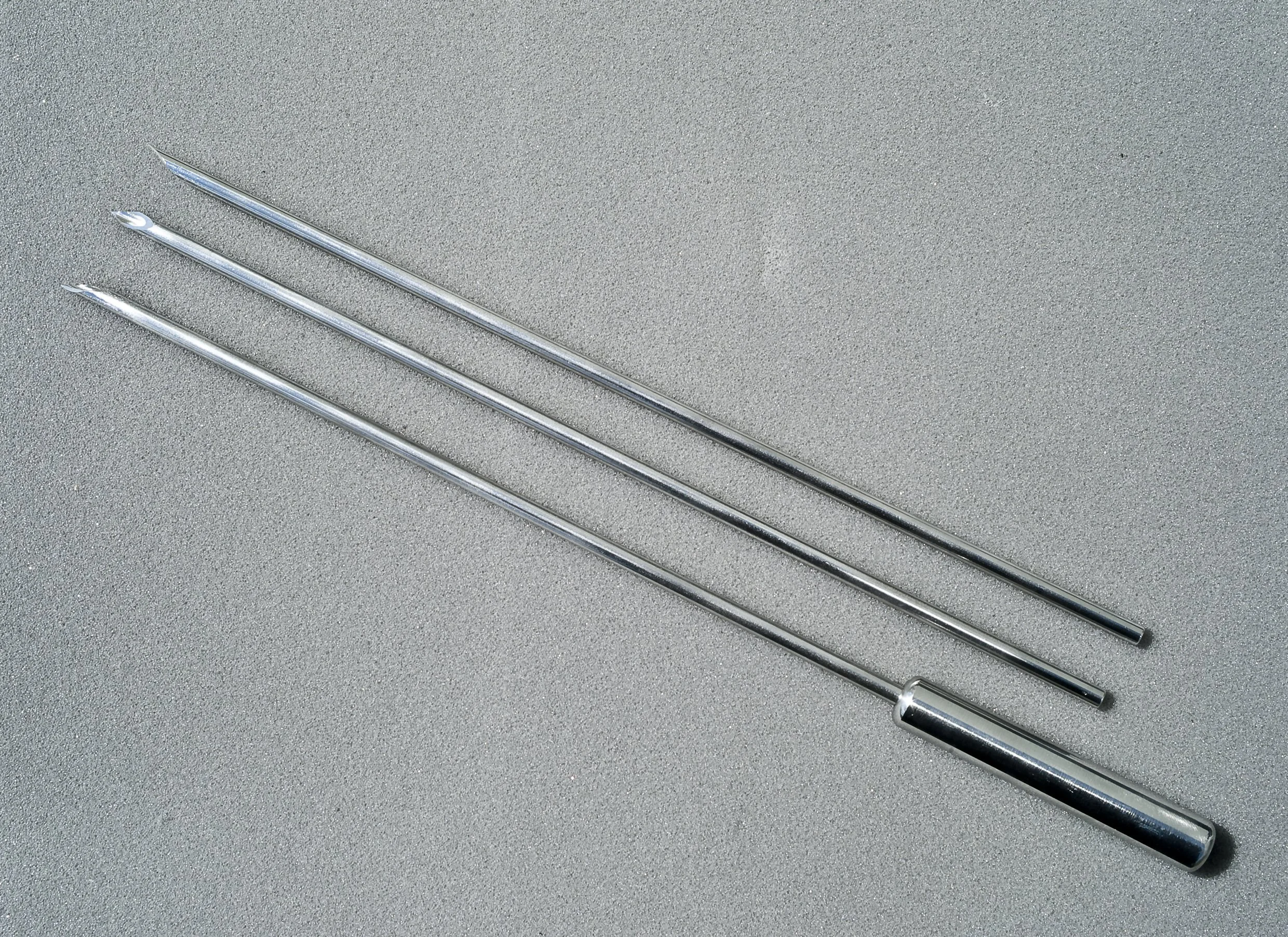 Three metal lock picking tools lying on a gray textured surface.