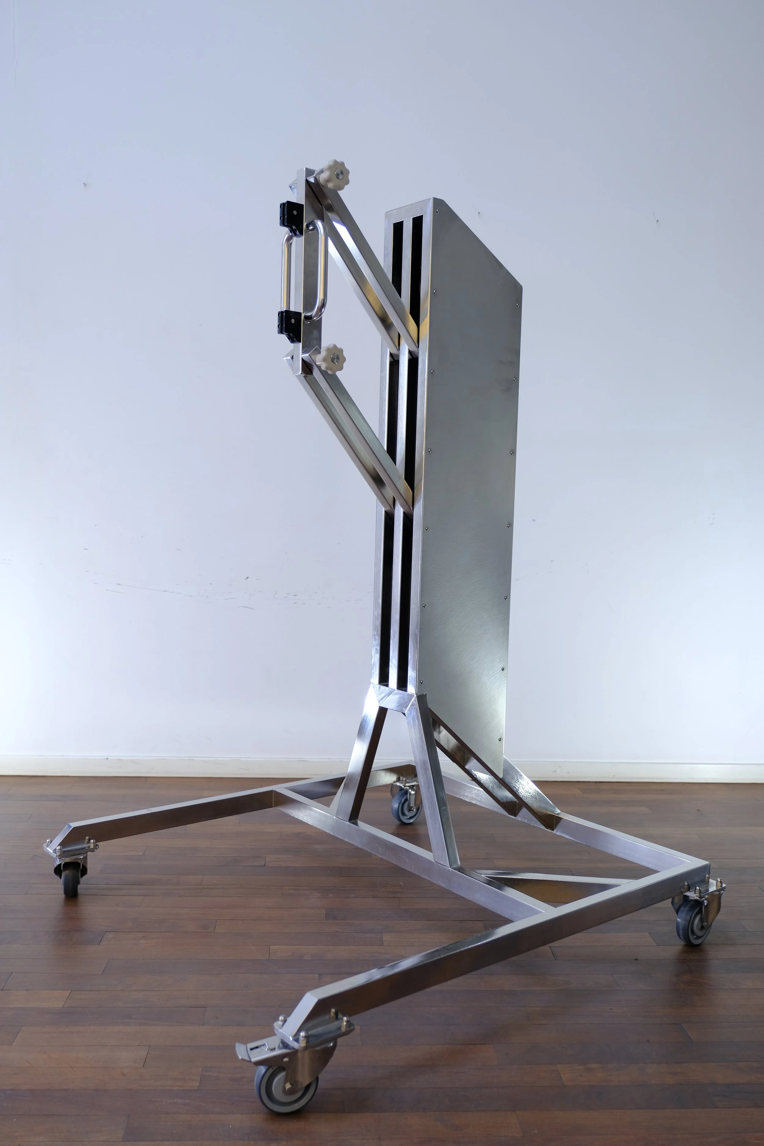 Metal medical or scientific equipment mounted on a wheeled stand.