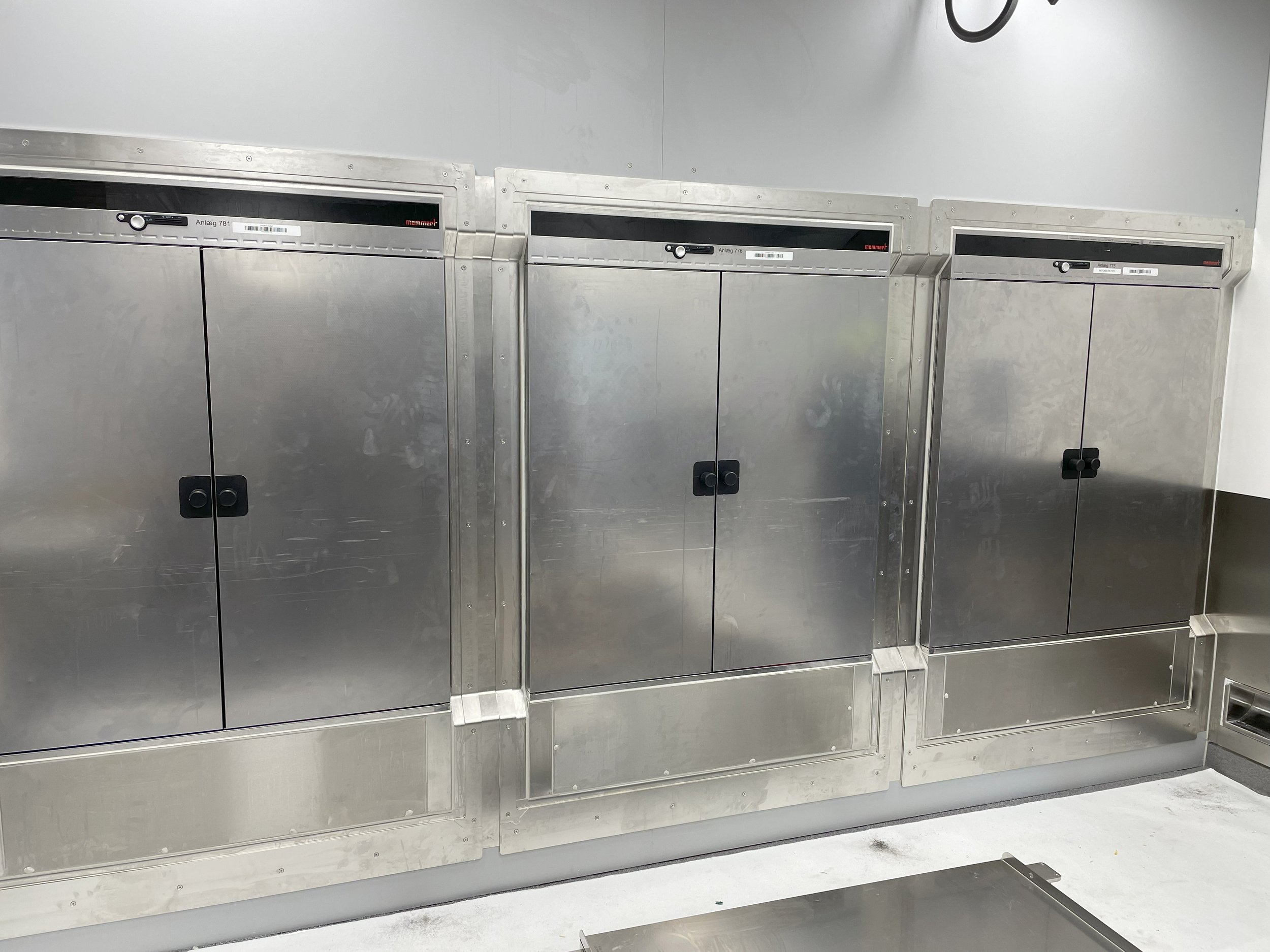 Three large stainless steel lockers with black handles, for pharma