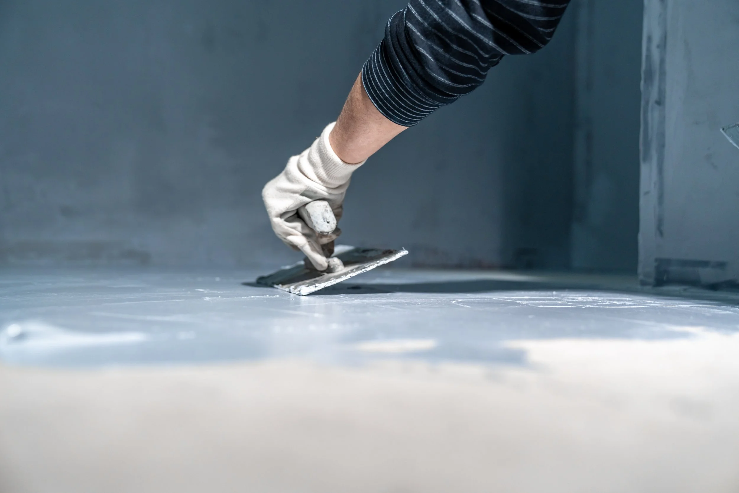Person applying a layer of ceiling or wall plaster with a trowel.