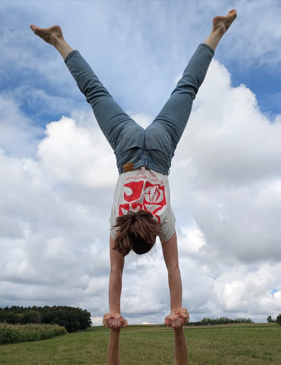 Karo balanciert mit BBBW-Logo-Shirt im Handstand auf den Händen eines Akrobatikpartners.