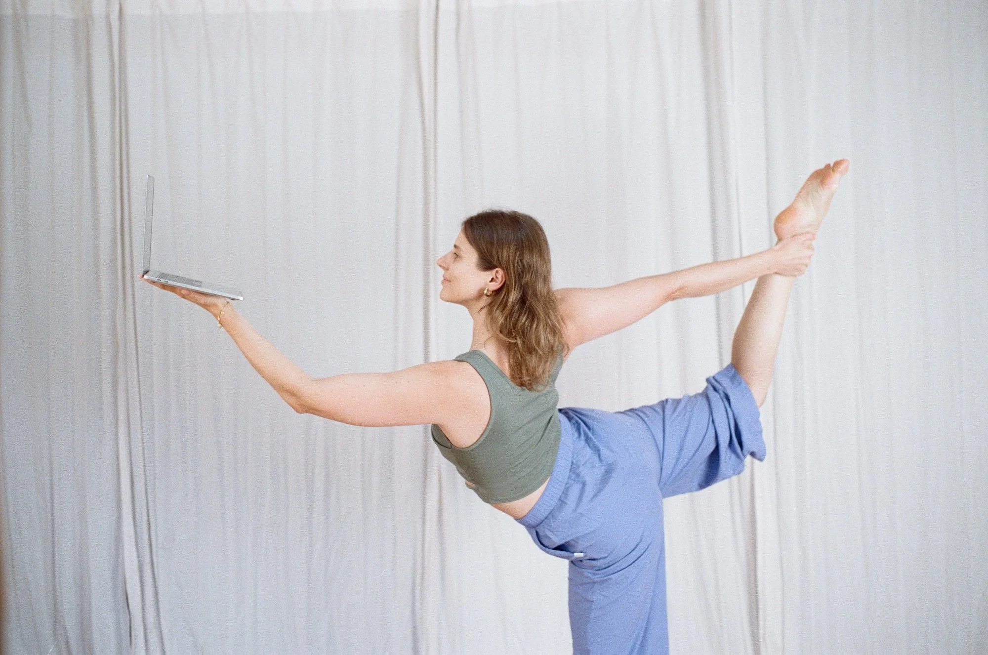 Eine Frau macht bei einem Online-Yoga Kurs vor einem Laptop