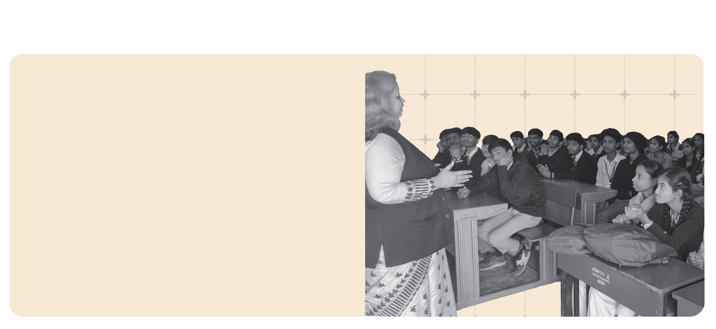 Teacher or speaker addressing a classroom of students seated at desks, listening attentively.