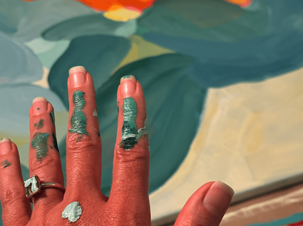 Artist Birgit Trofer's hand working on a new painting, covered with turquoise and green hues of the new color palette.
