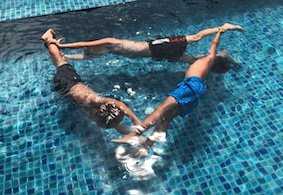 Three boys swimming in a pool, forming a triangle.
