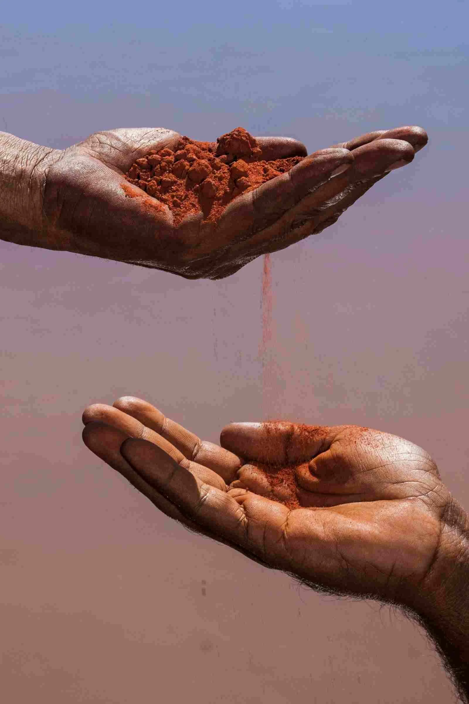 Two hands on top of each other with sand passing between indicating ancestral wisdom