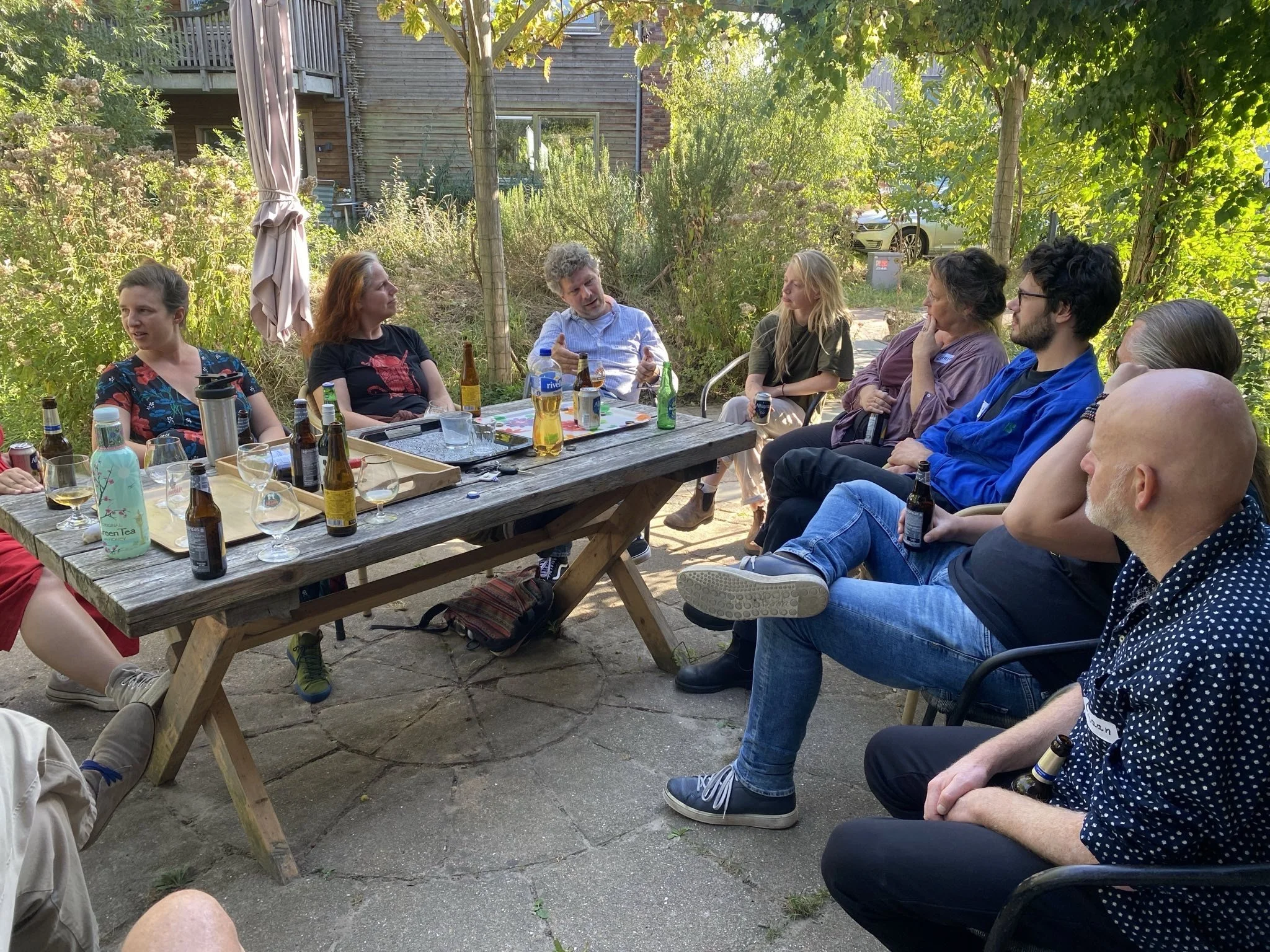 A large whiteboard with a grid background filled with colorful sticky notes in yellow and pink, organized into categories about teams, budgets, and activities for a project or event planning.