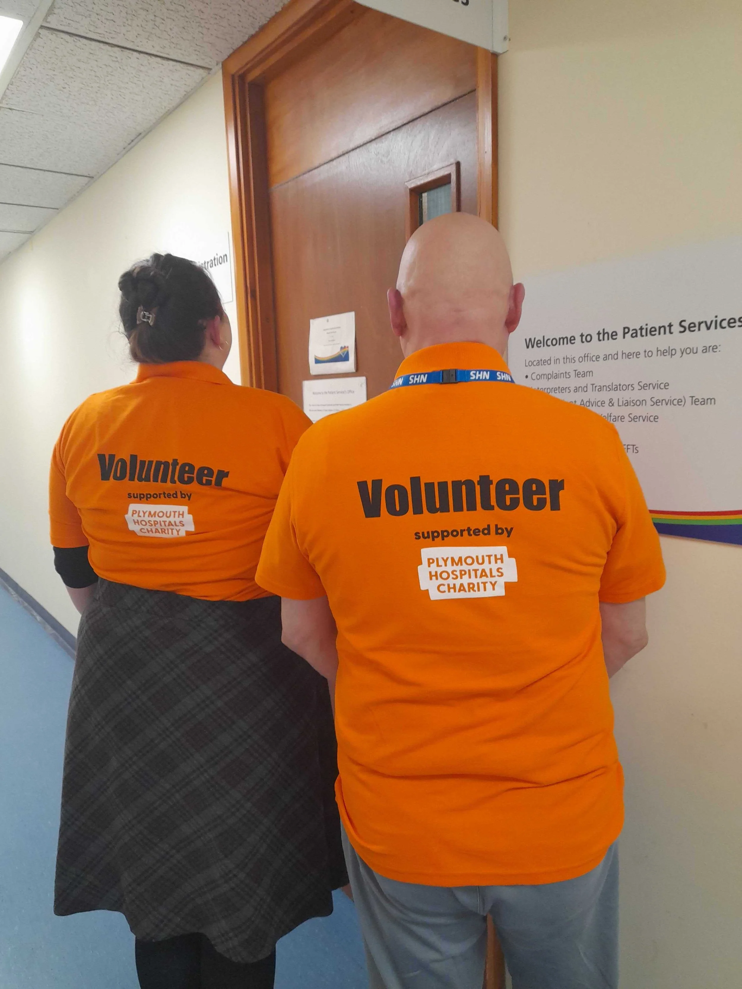 The back of Danielle and Mark’s new bright orange polo shirts. It says: Volunteer supported by Plymouth Hospitals Charity 