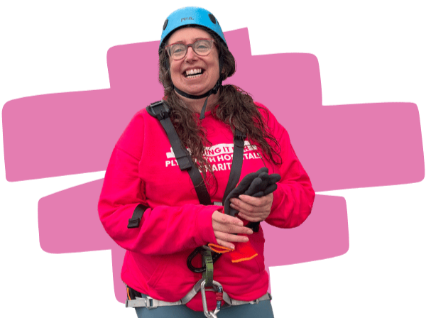 Photo of Tracey smiling after completing the abseil, with a transparent background and a pink decorative highlighter swoop behind her.