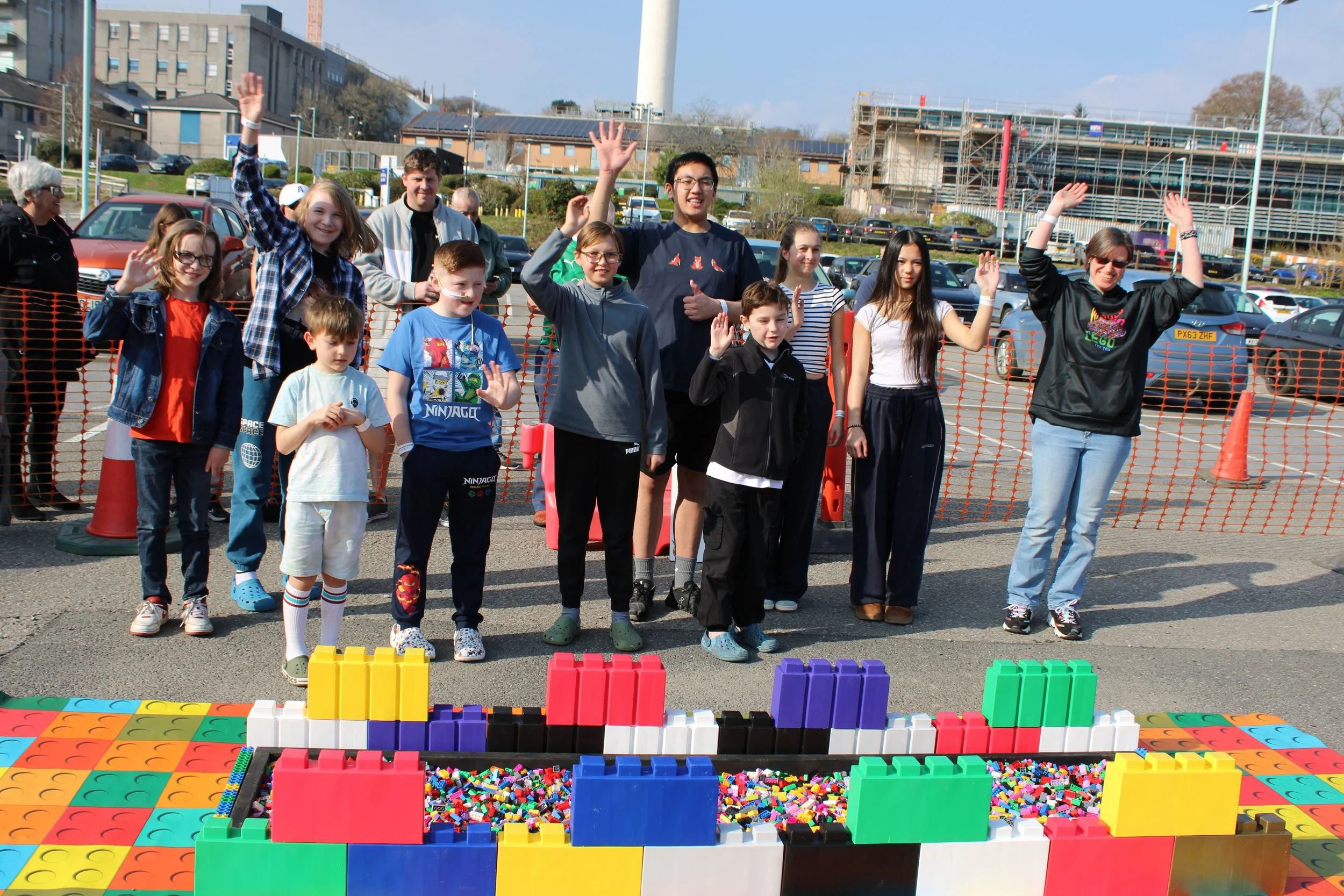 Group photo of fundraisers with their hands in the air in front of the Lego path