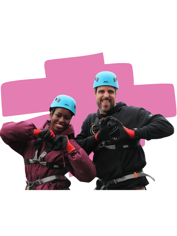 Photo of two members of the cardiology team smiling and making a heart shape with their hands after taking part in the abseil. The background has been removed and replaced with a decorative pink highlighter swoop.